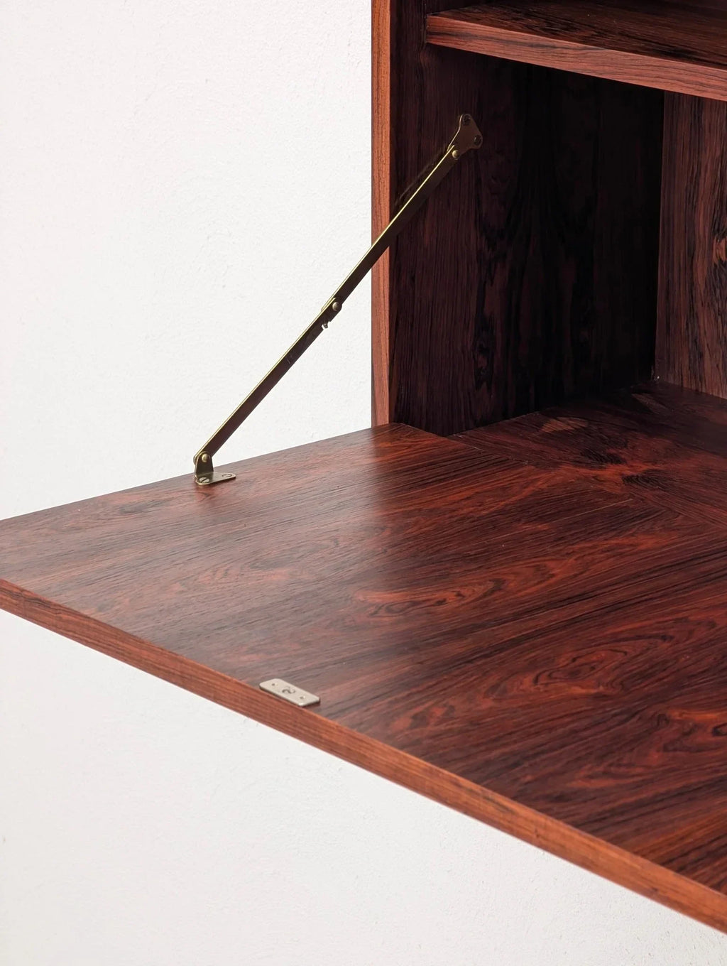 Danish modern floating cabinet with bookmatched rosewood drop-down door, brass hinge detail