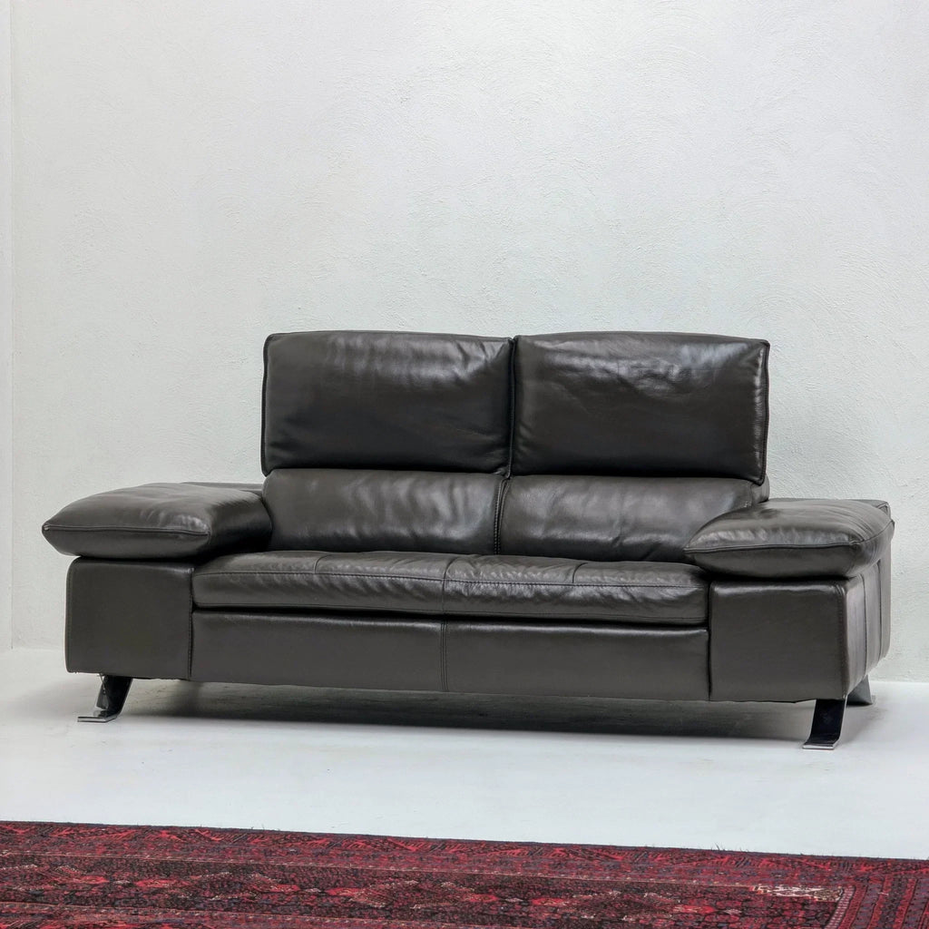 Domicil Butterfly black leather sofa with wide arms on white wall and red rug