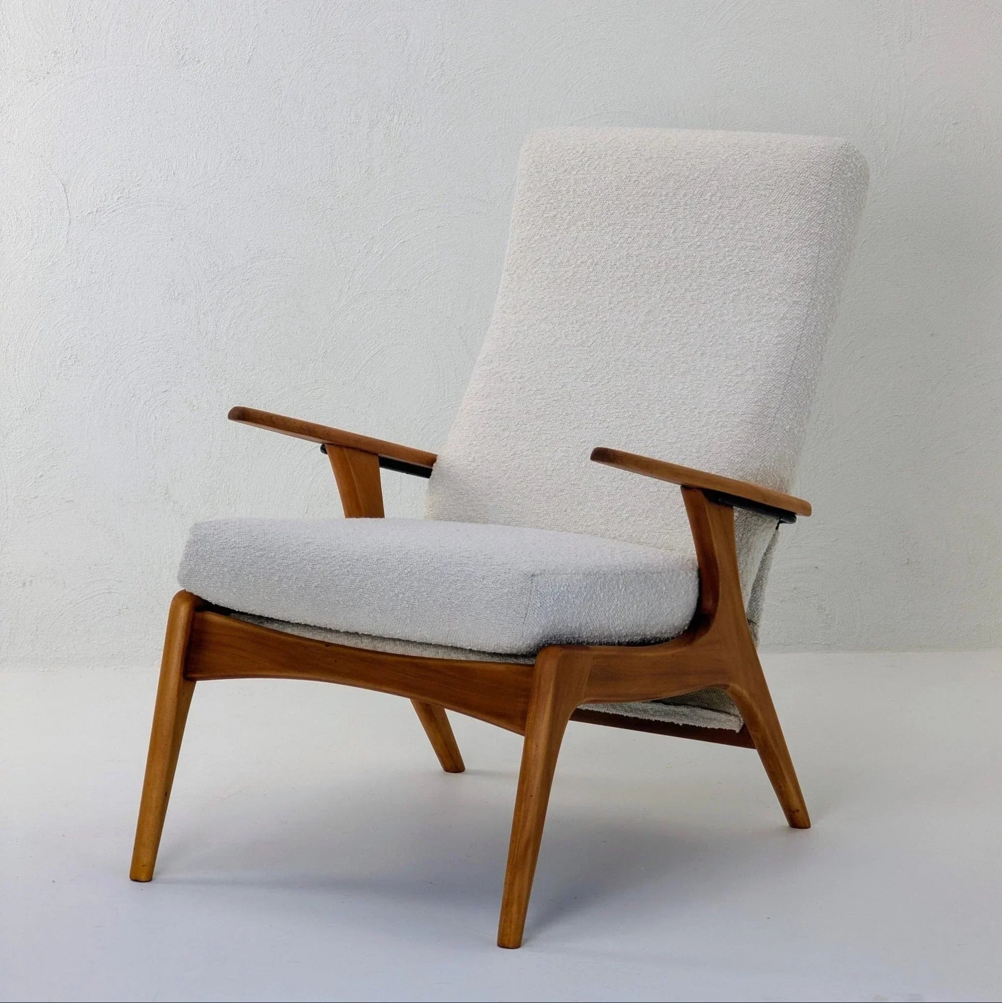 Modern armchair with creamy white boucle upholstery and wooden frame on plain background