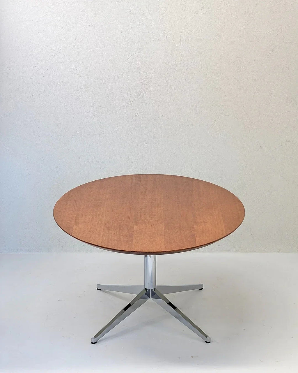 Mid-century oval oak table desk with chrome pedestal base against plain white wall