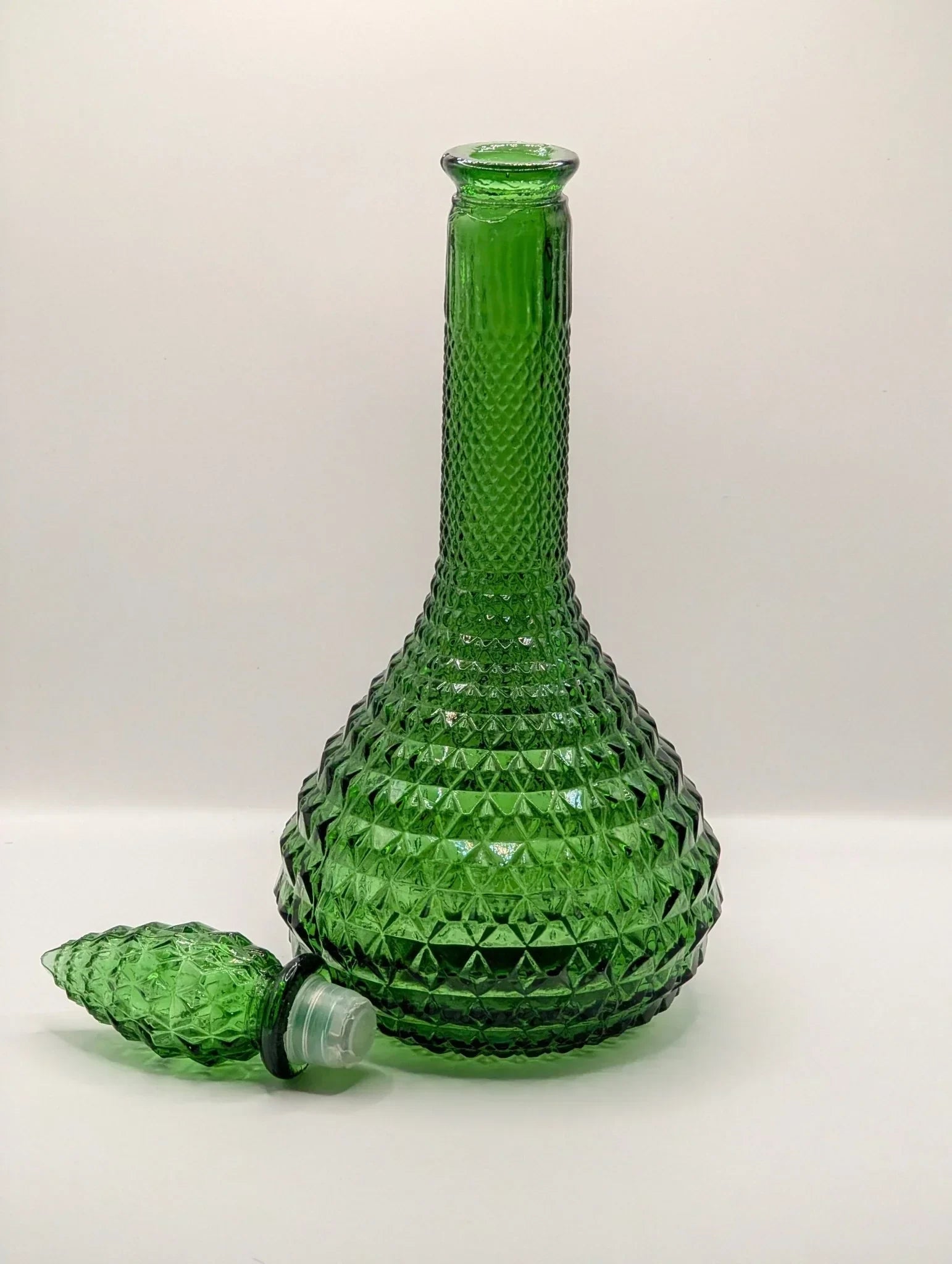 Green diamond-pattern Empoli glass genie bottle decanter with stopper on white background