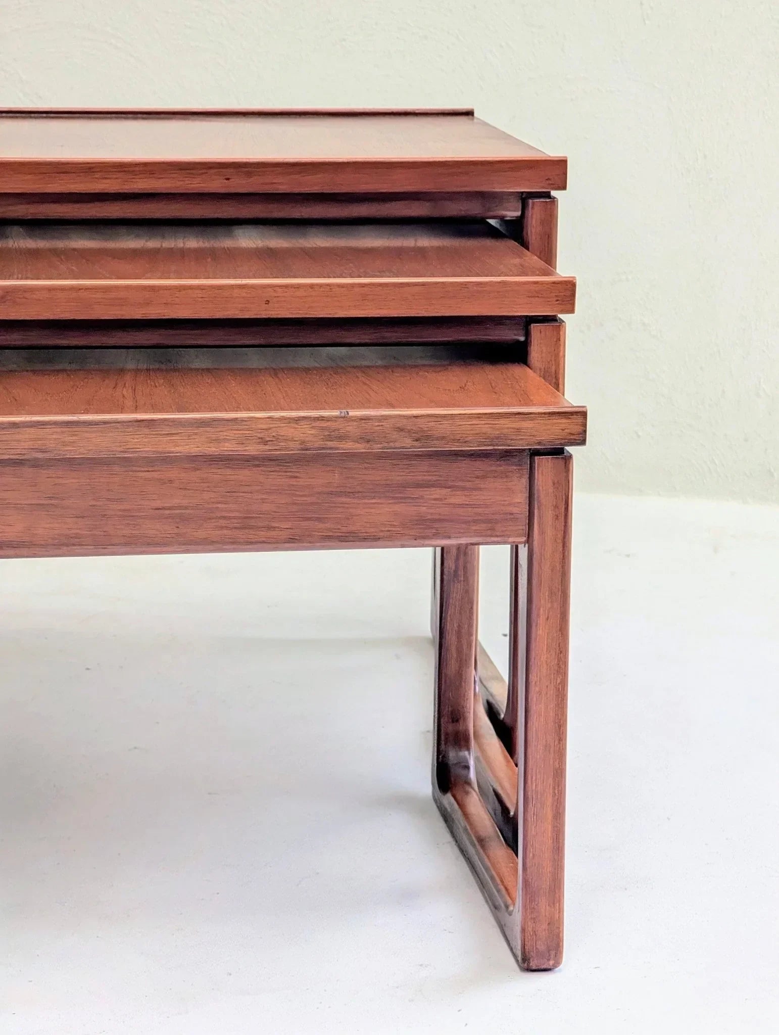 Mid-century teak nesting tables with modular design against a light background