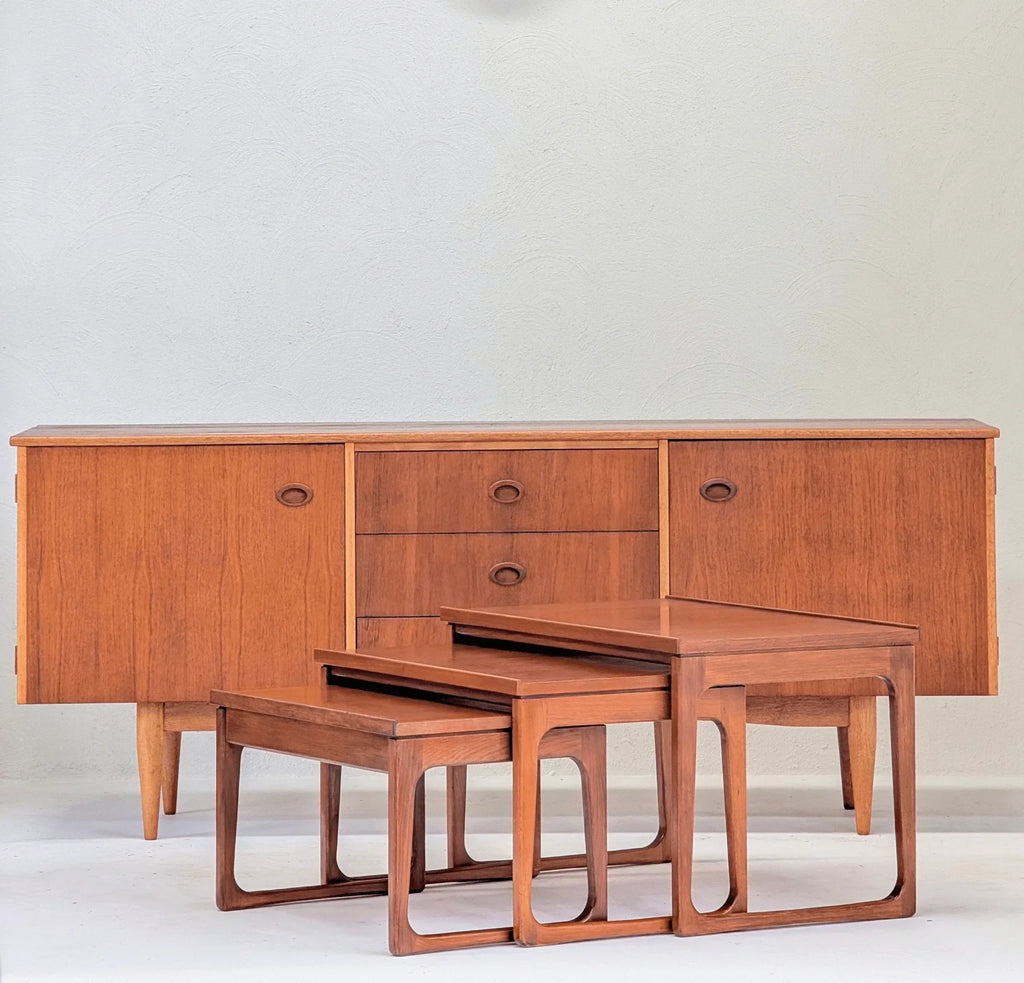 Mid-century teak nesting tables and sideboard on white background