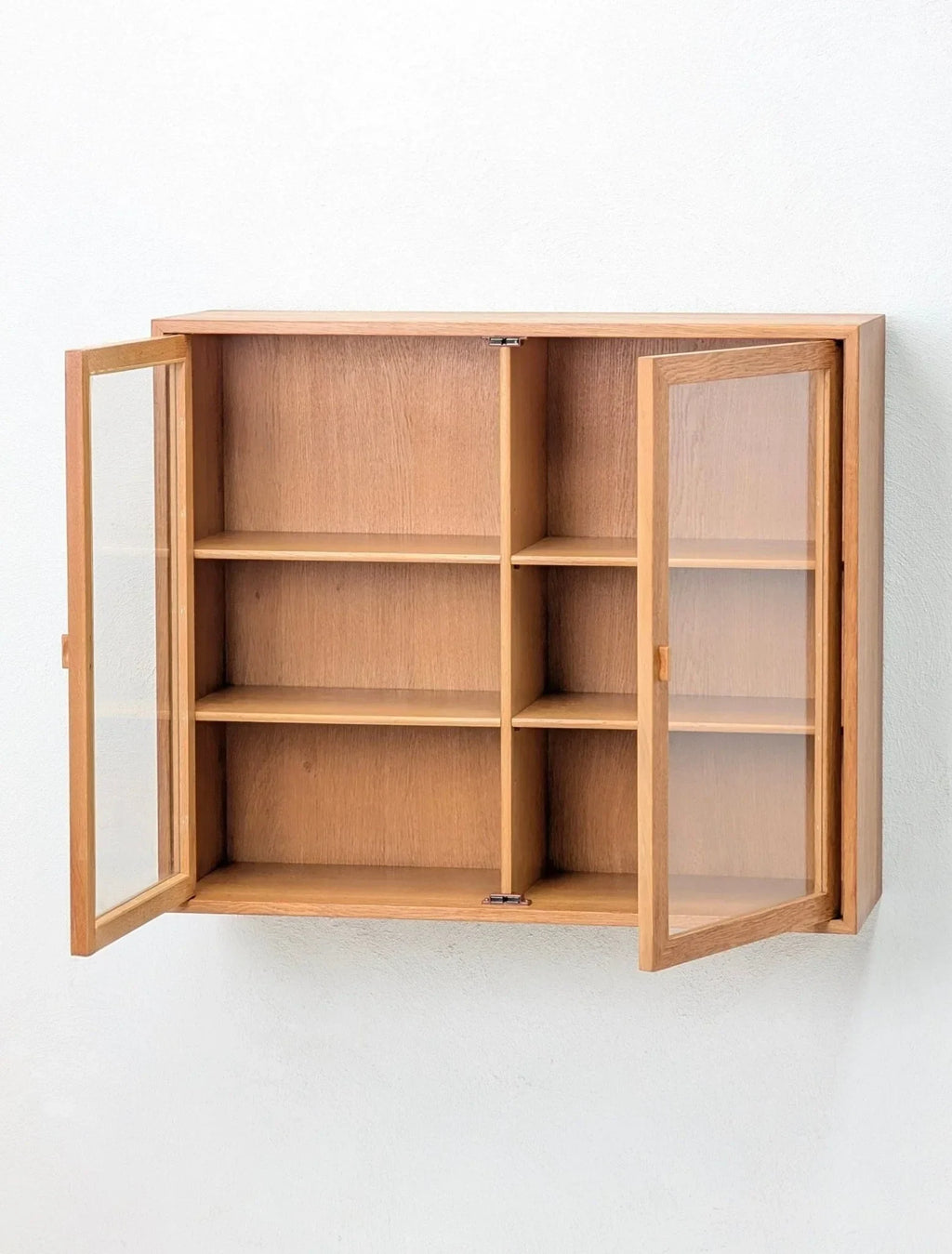 Mid-century oak and glass wall display cabinet with open doors and shelves