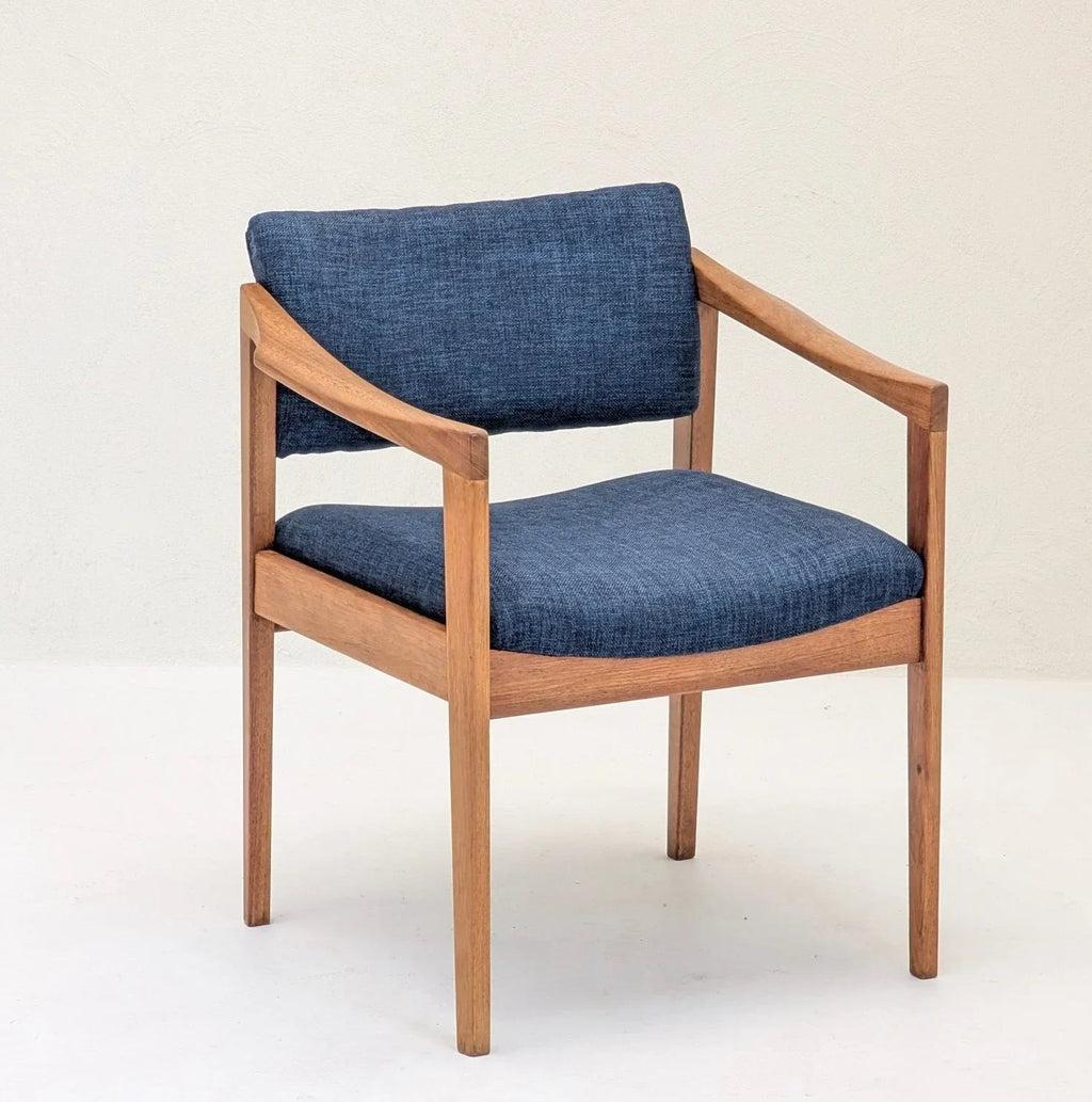 Mid-century modern armchair with wooden frame and blue fabric upholstery on light background