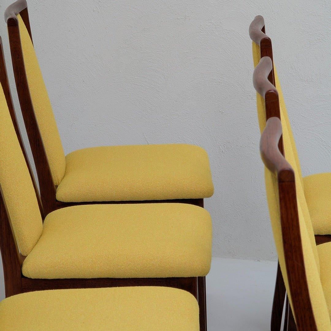 Mid-century modern dining chairs with yellow upholstery and wooden frames