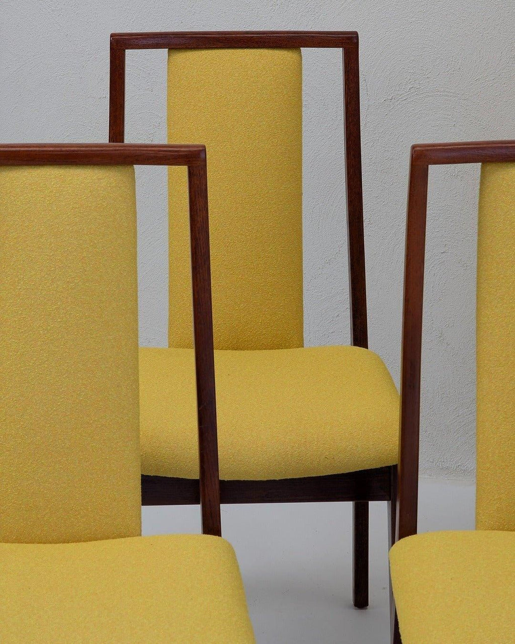Mid-century modern dining chairs with yellow upholstery and wooden frames