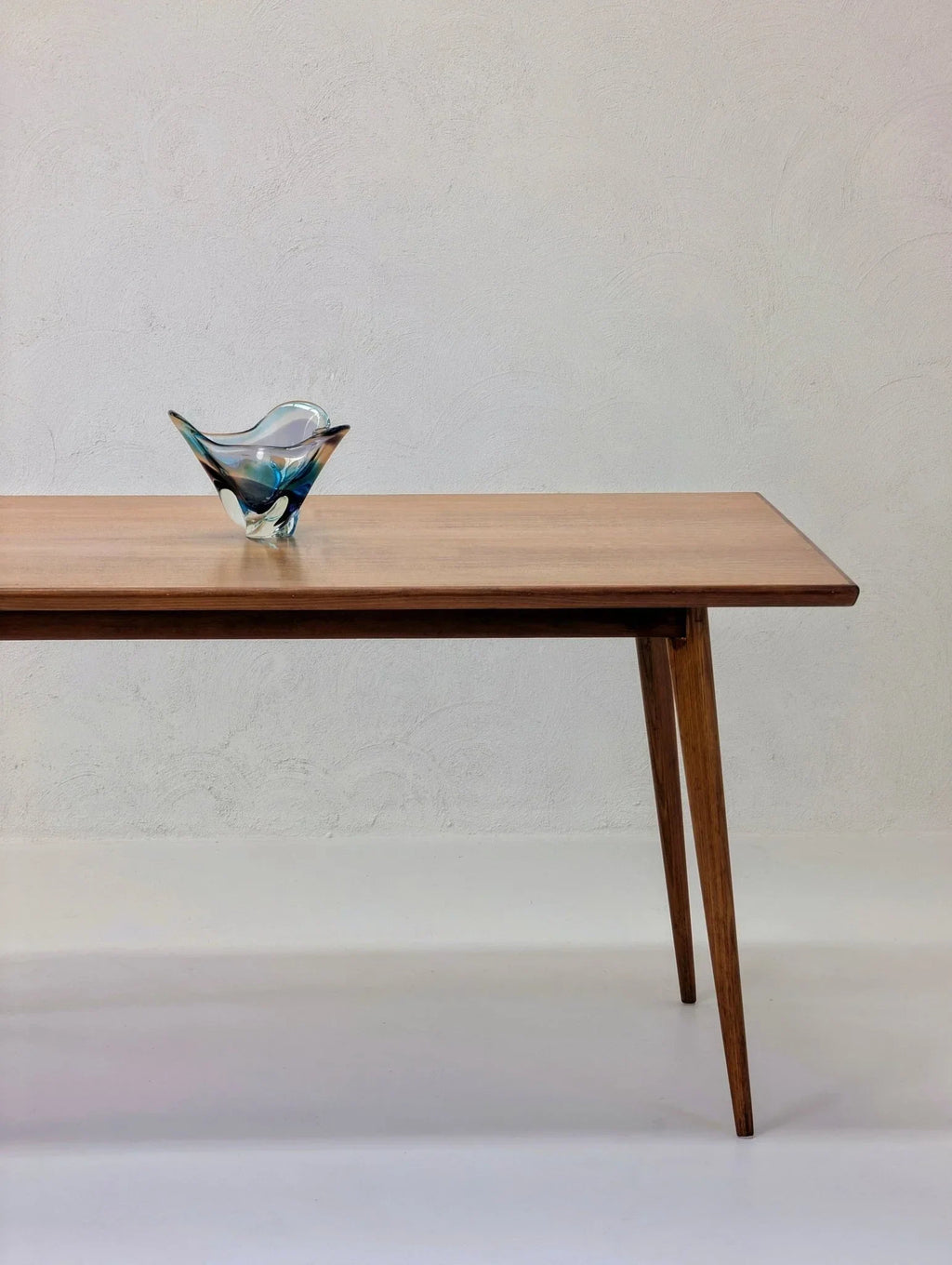 Mid-century modern dining table in golden teak wood with art glass bowl on top