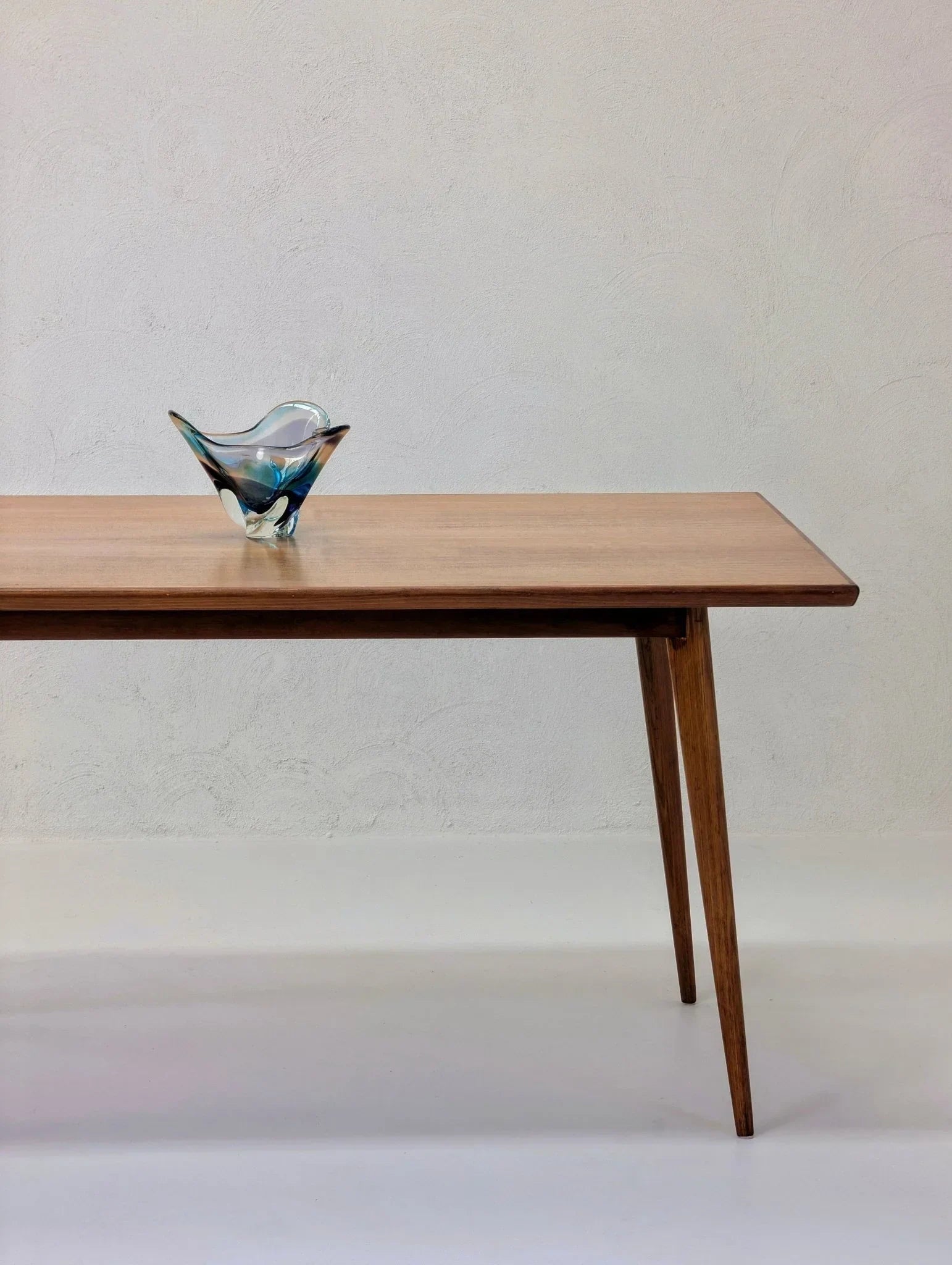 Mid-century modern dining table in golden teak wood with art glass bowl on top