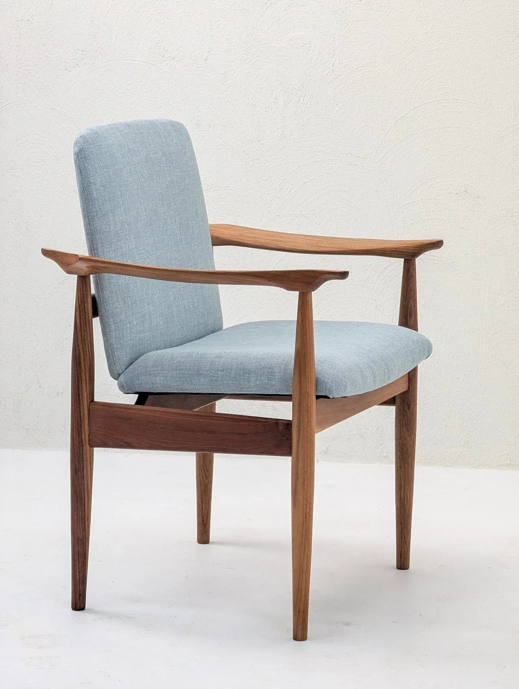 Mid-century modern teak armchair with sculptural arms and light blue upholstery