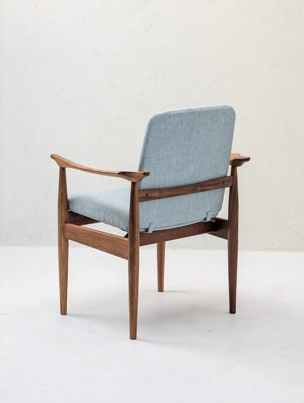 Mid-century modern sculptural armchair with light blue upholstery and teak wood frame