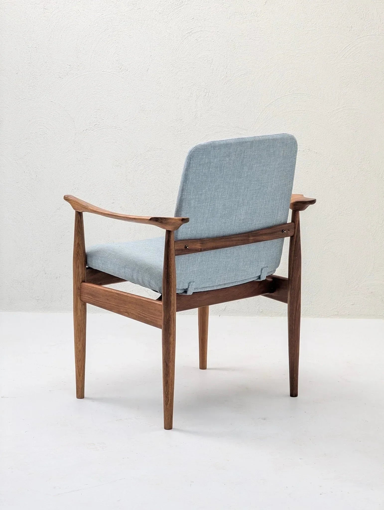 Mid-century modern sculptural armchair with light blue upholstery and teak wood frame