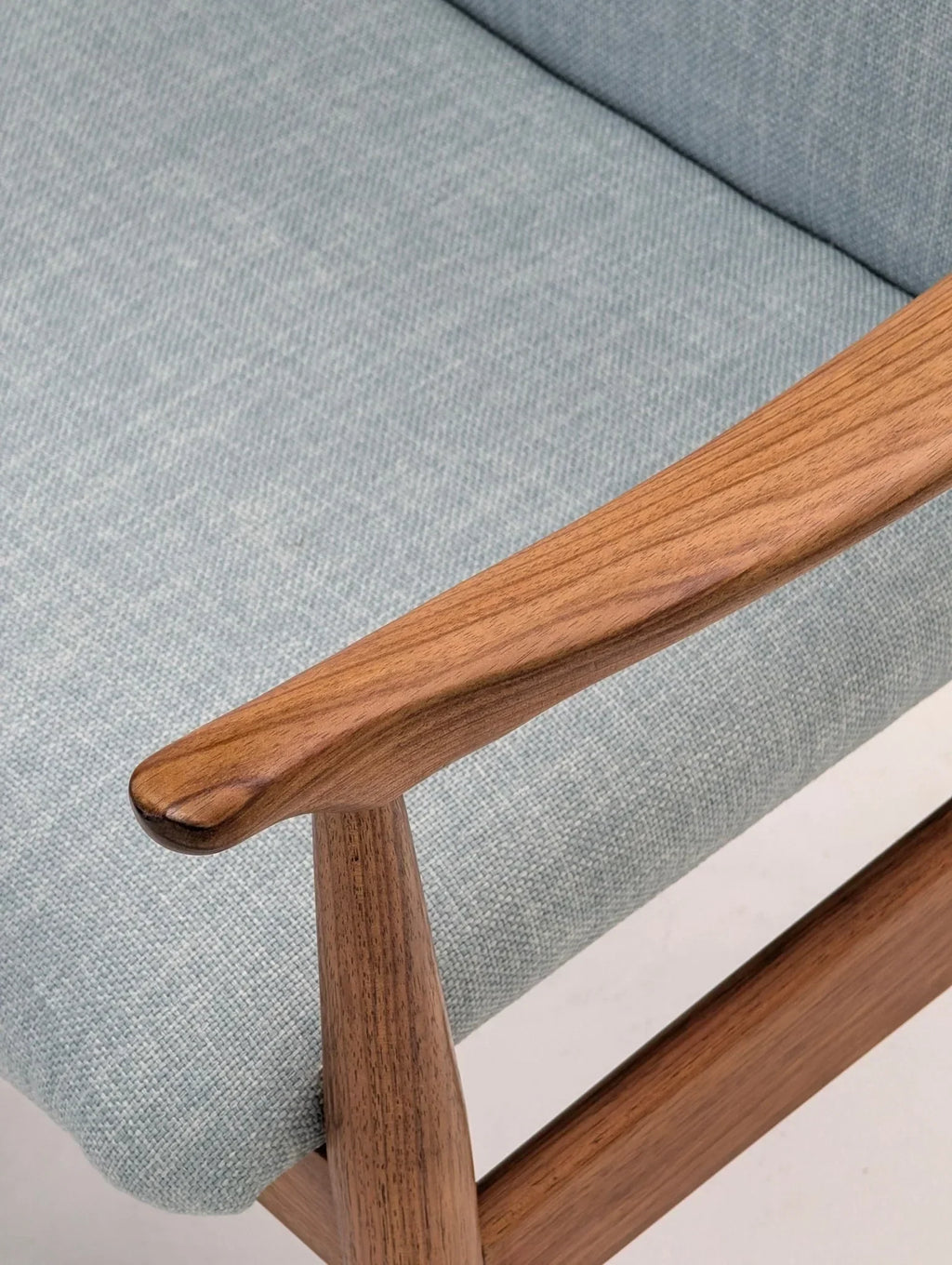 Mid-century modern teak and blackwood armchair with light blue fabric upholstery