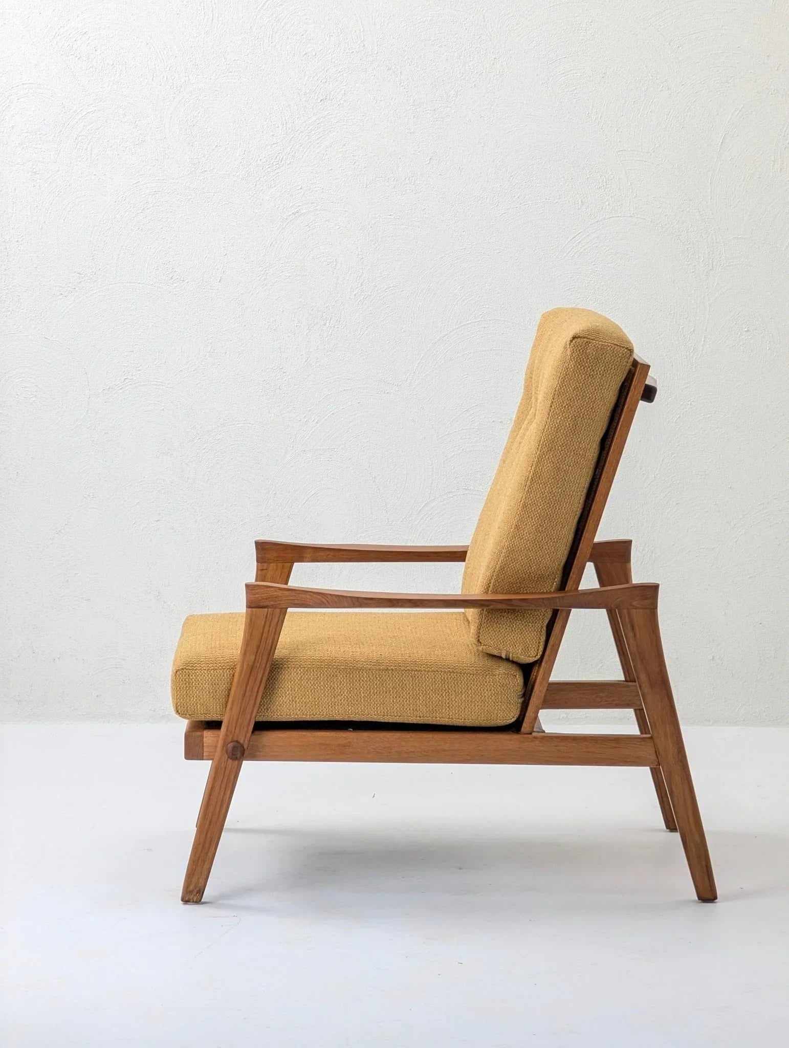 Mid-century modern solid teak lounge chair with mustard upholstery, white background