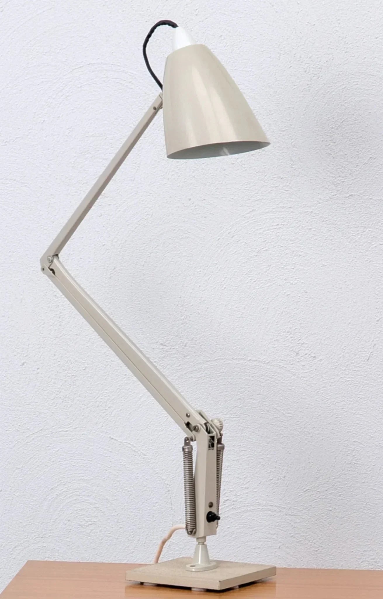 Mid-century modern studio K task lamp on wooden desk against white textured wall