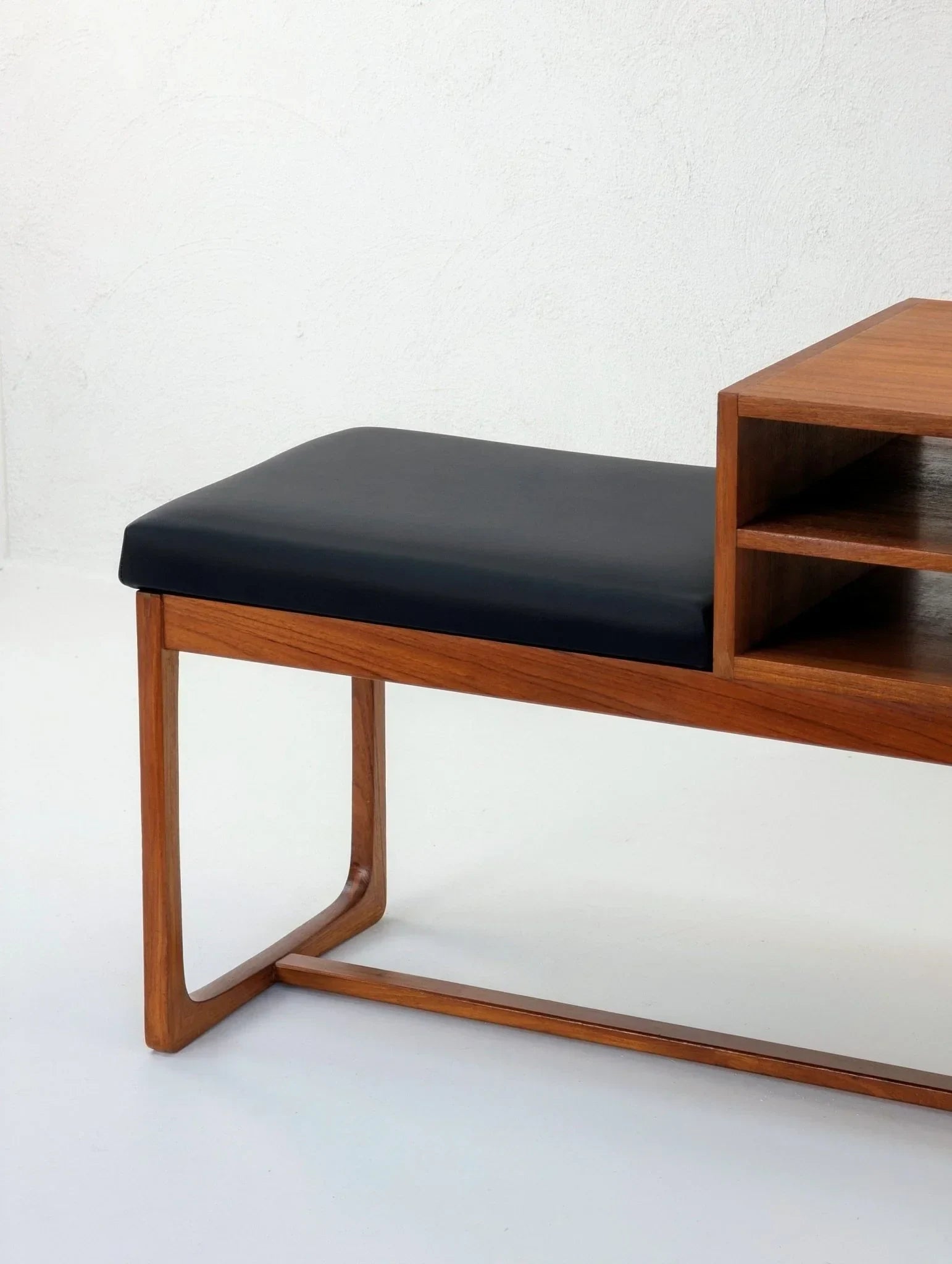Mid-century teak telephone table with black cushioned seat and open shelf design