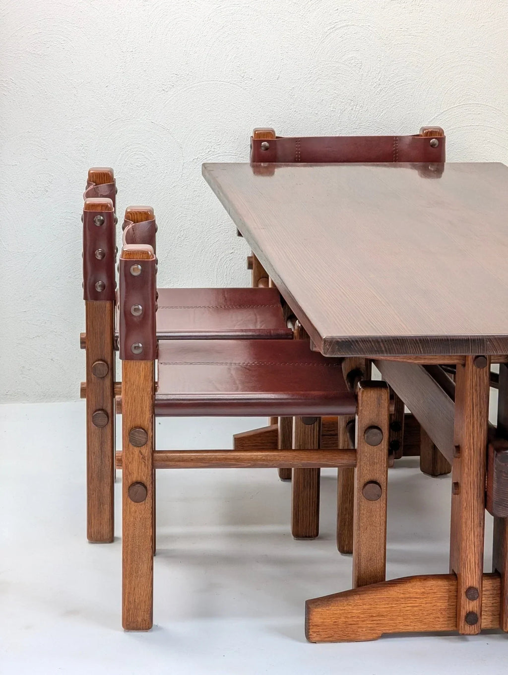 Set of 1970s vintage dining chairs with brown leather backs and wooden frames at table