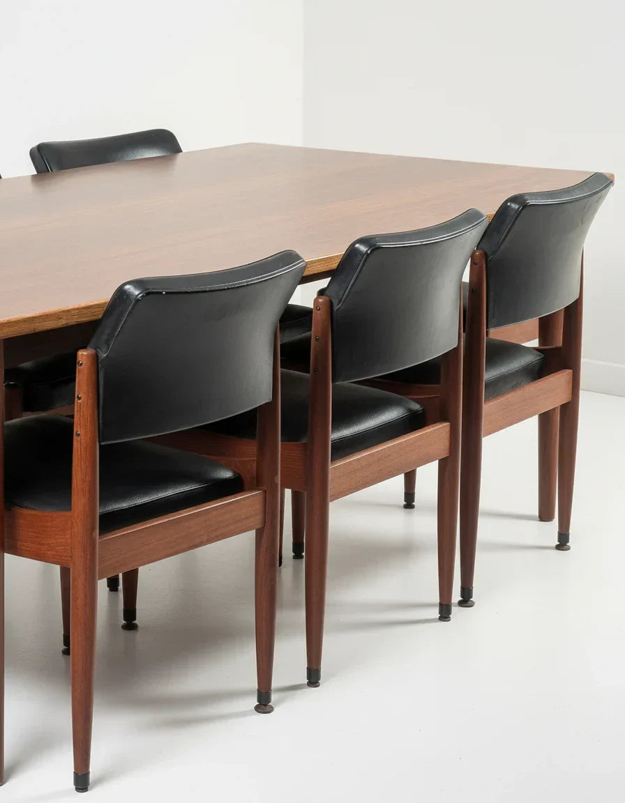 Mid-century modern dining table with black leather chairs and wooden legs in minimalist room