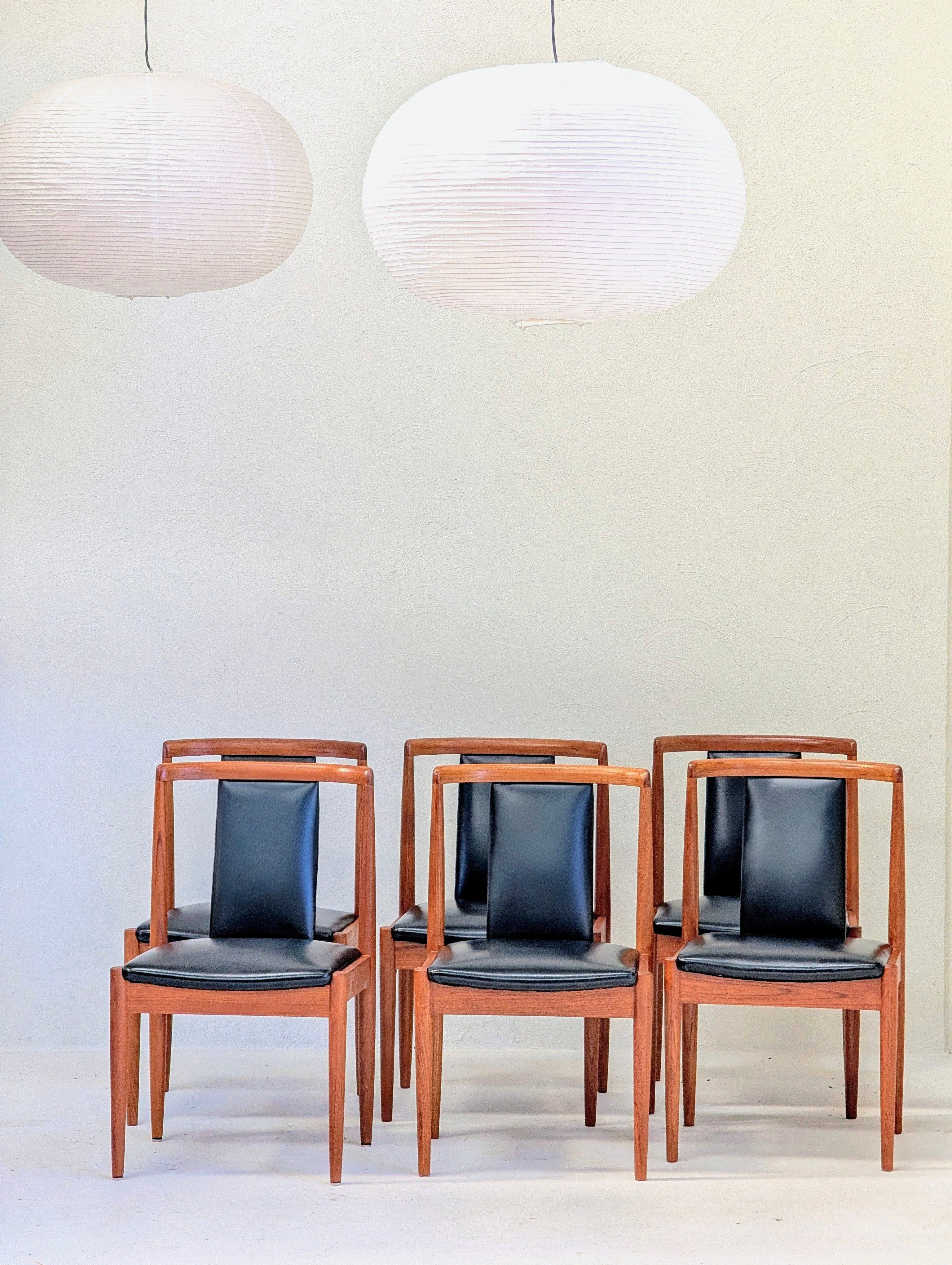 Set of six mid-century modern dining chairs with black seats under white paper lanterns
