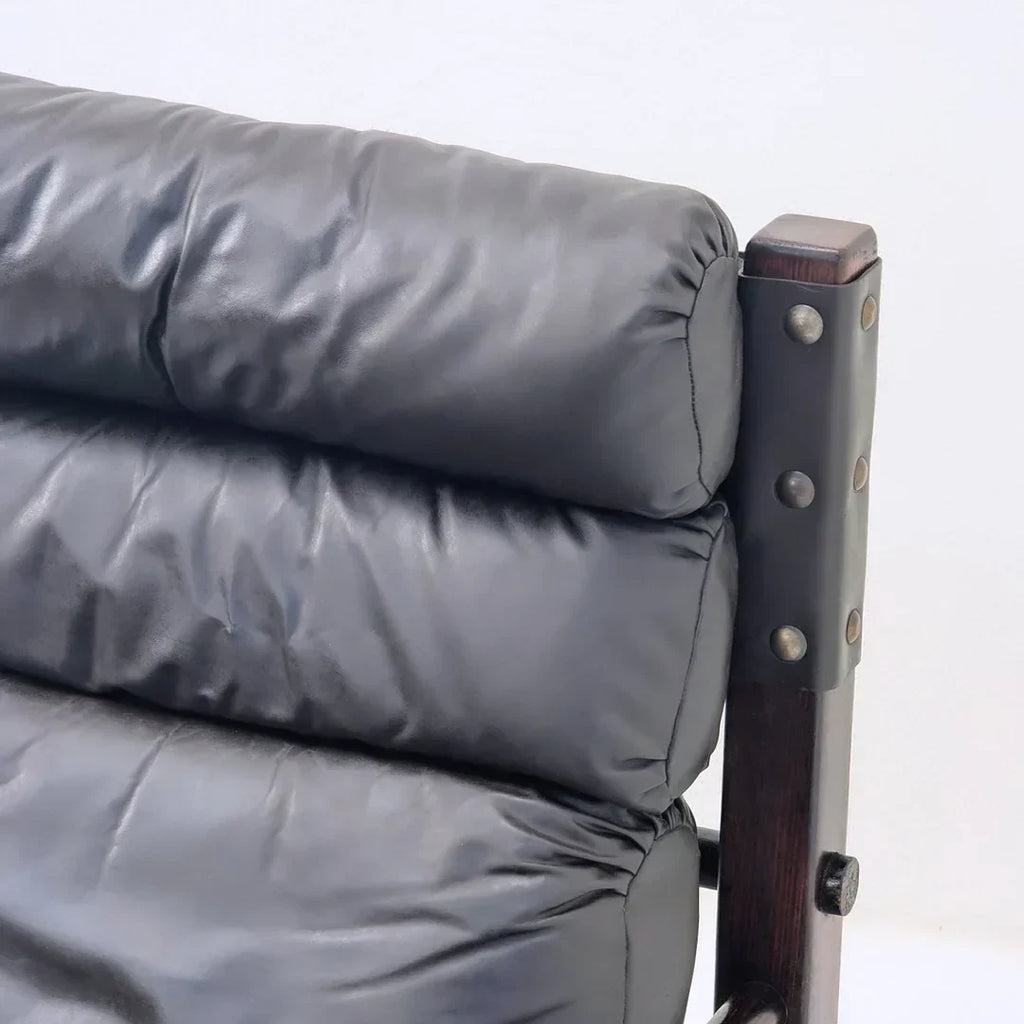Close-up of black leather cushioned chair with dark wood frame and metal rivets