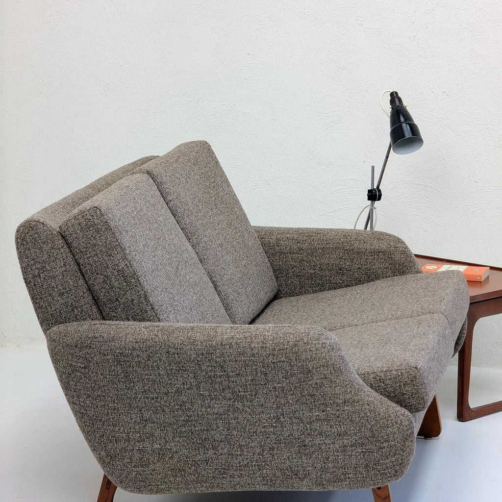 Mid-century modern gray sofa with a wooden side table and black desk lamp in minimalist room