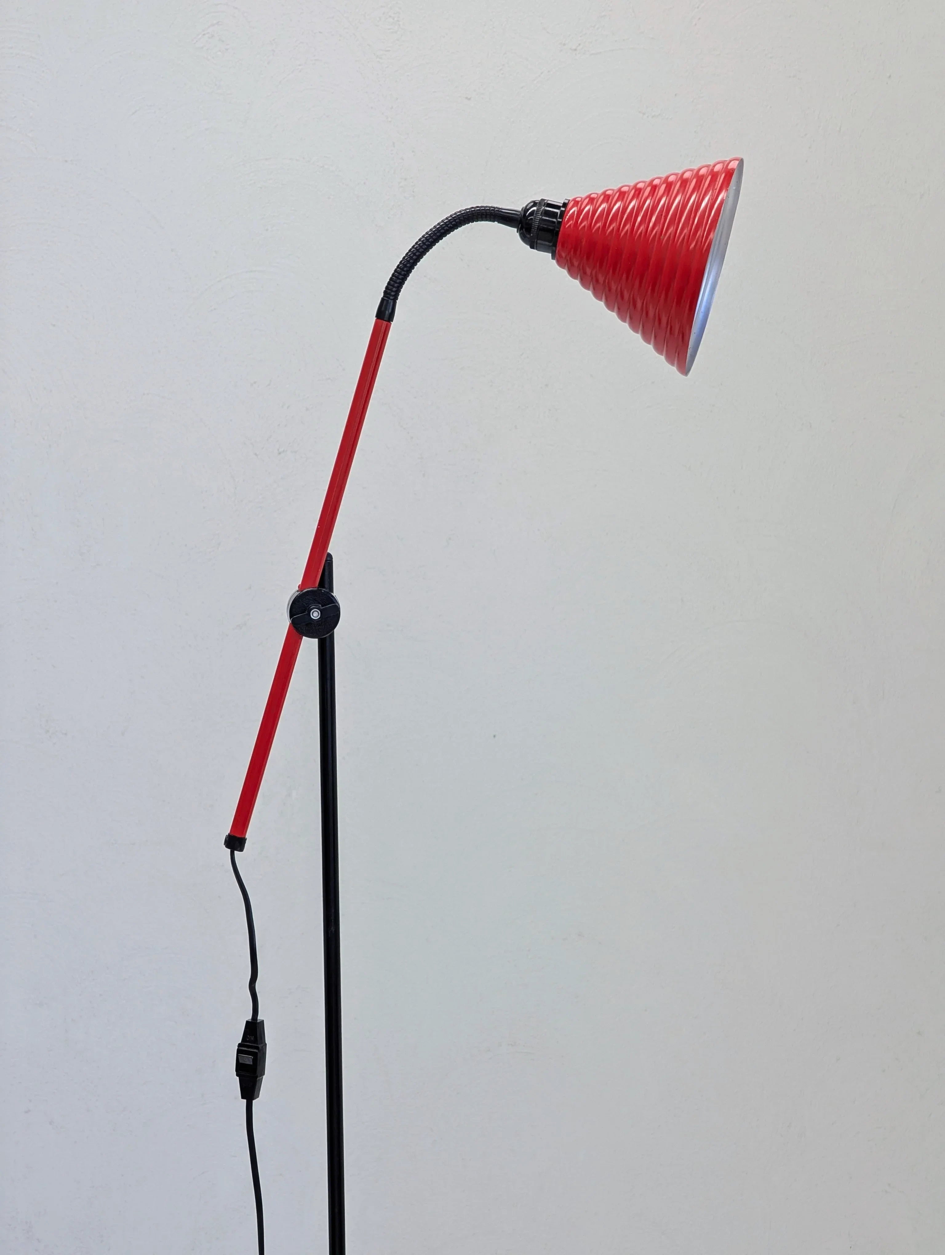 Modern floor lamp with red and black adjustable arm and ribbed conical lampshade
