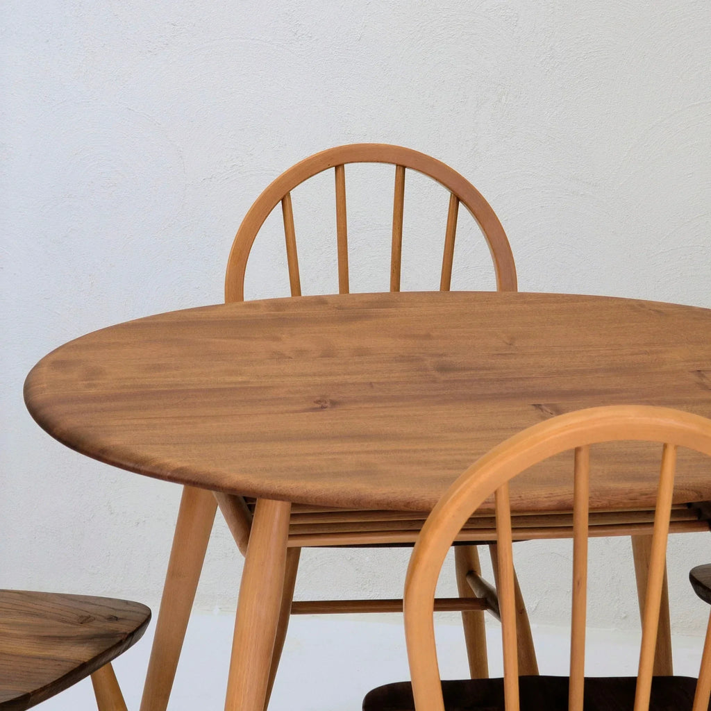 Round wooden dining table with matching spindle back chairs against a light wall