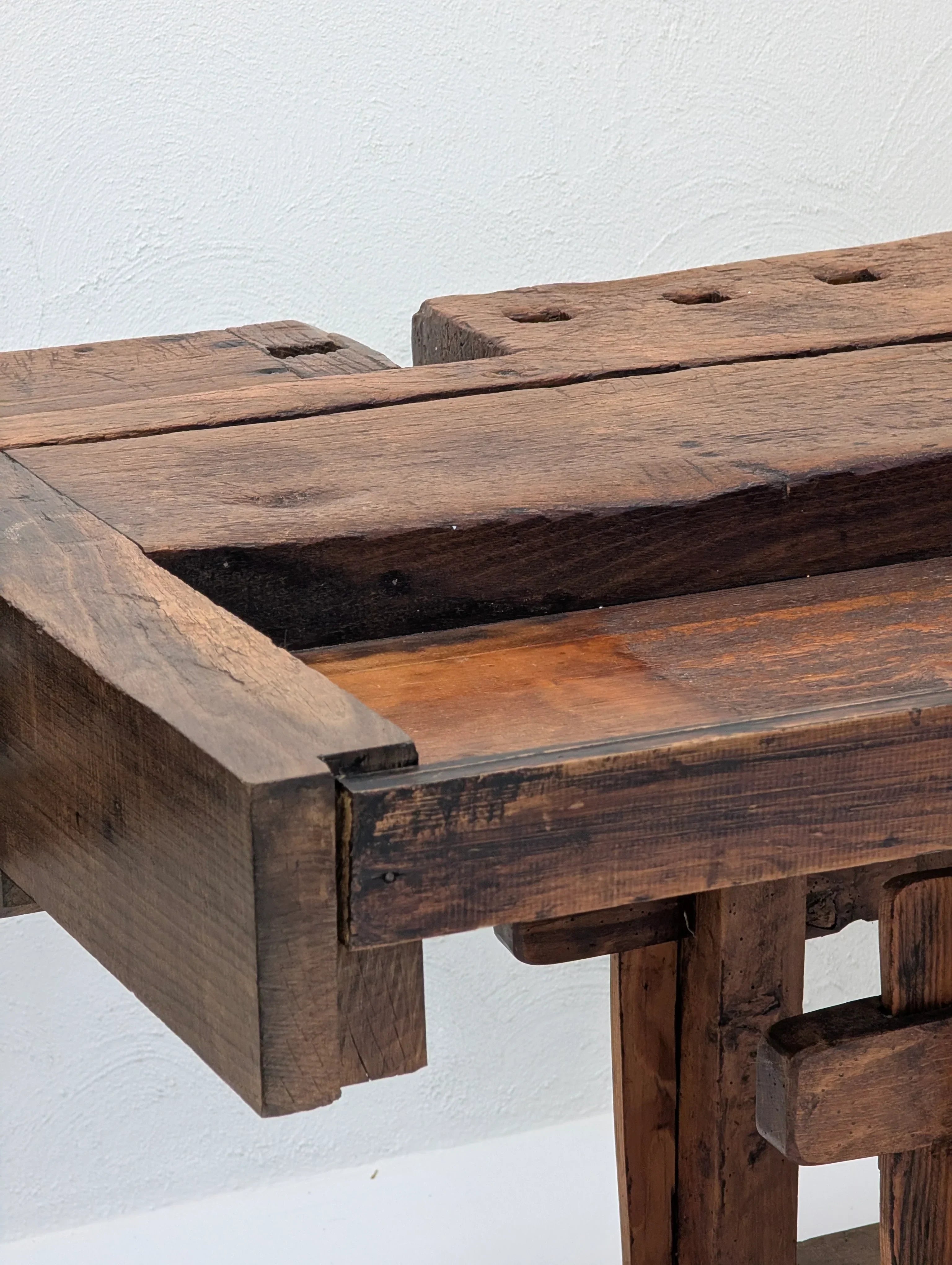 Close-up of rustic antique wooden workbench with visible joints against white wall