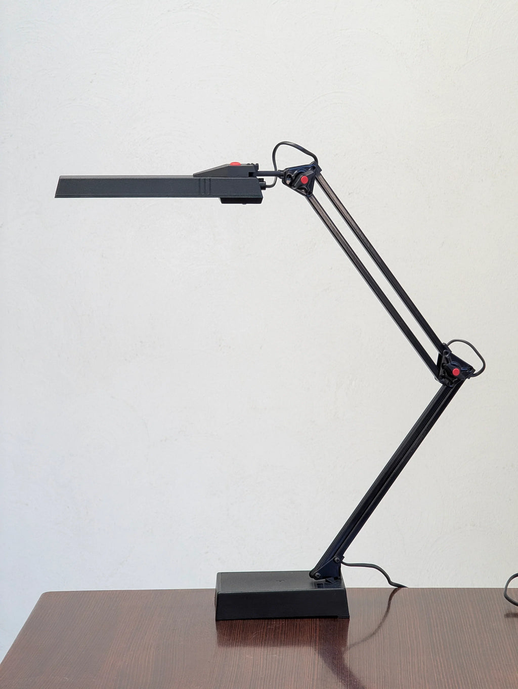 Modern adjustable black desk lamp on wooden table against white wall
