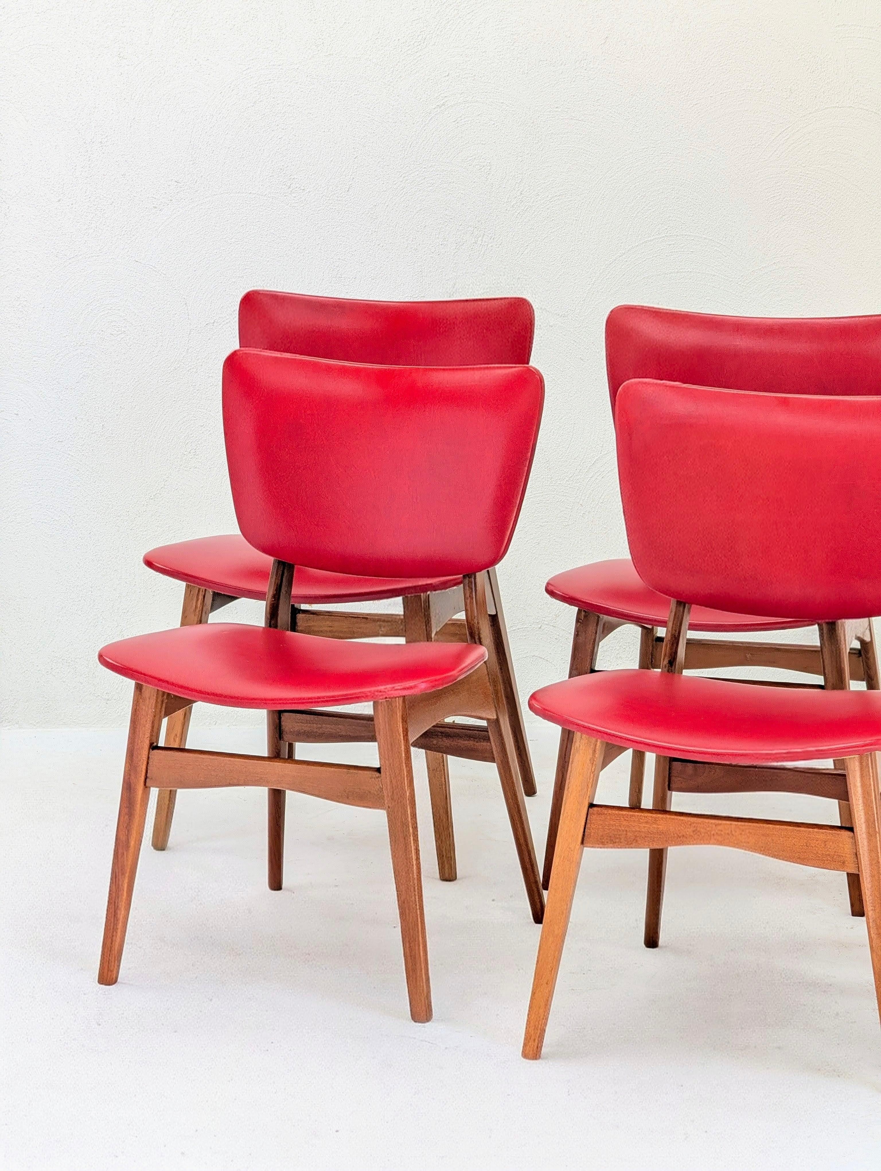 Set of four mid-century modern red chairs with wooden legs against a white background
