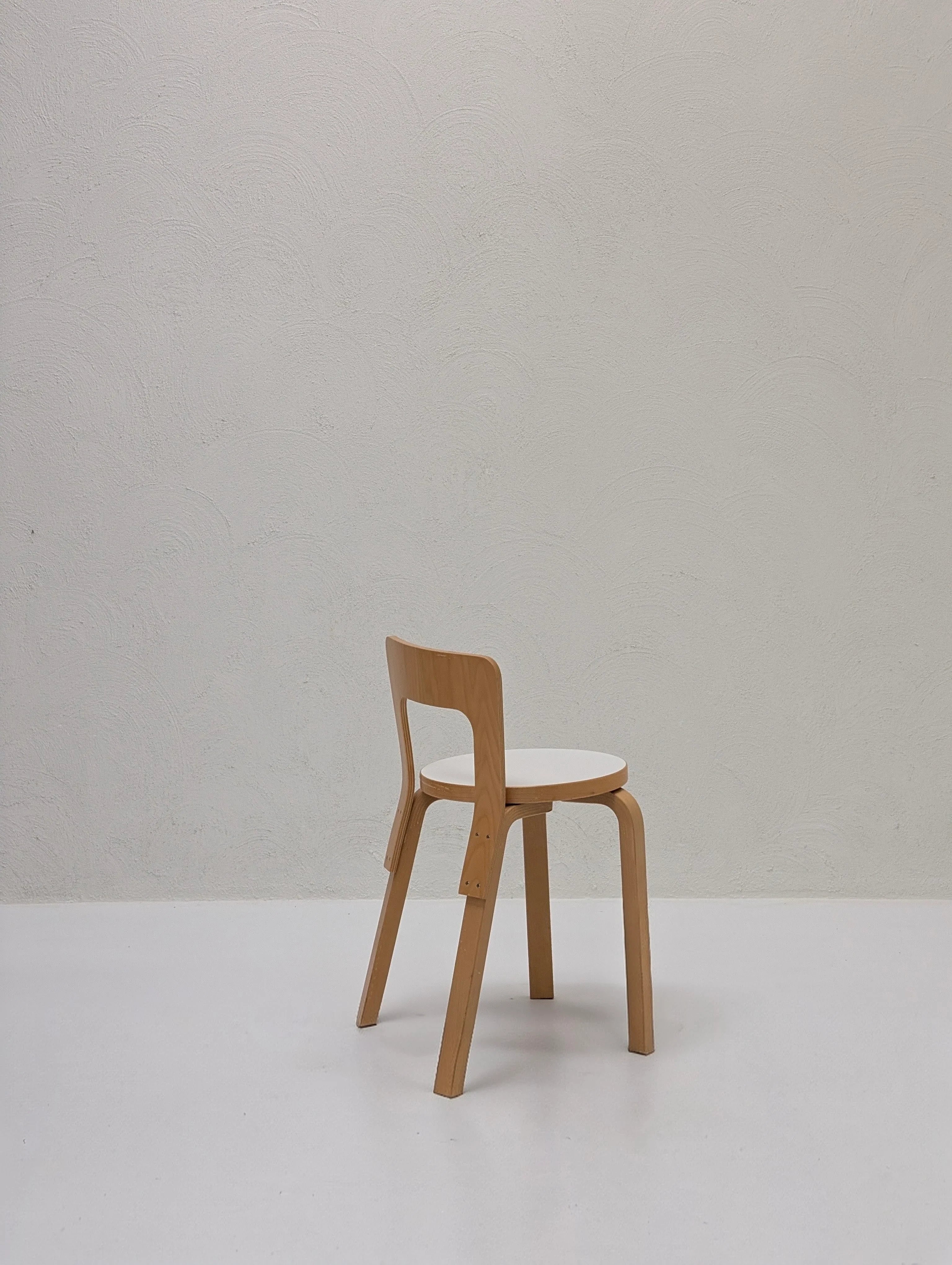 Minimalist wooden chair with white seat in empty room with textured white wall