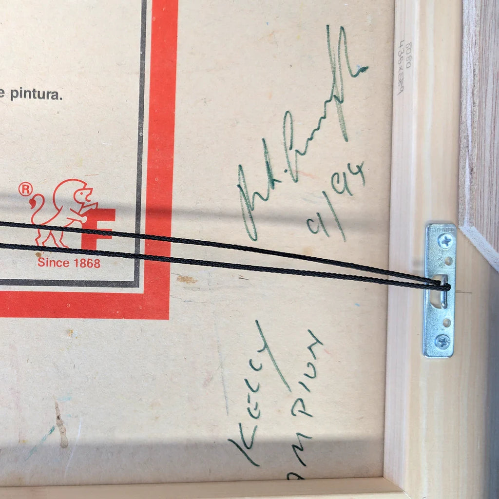 Back of framed artwork with F lion logo, hanging wire, handwritten signatures, wood frame