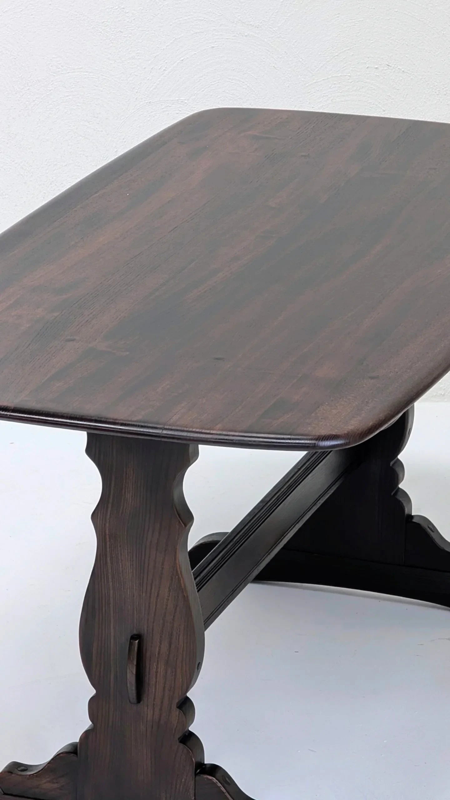 dark wood rectangular dining table with carved pedestal base on white floor