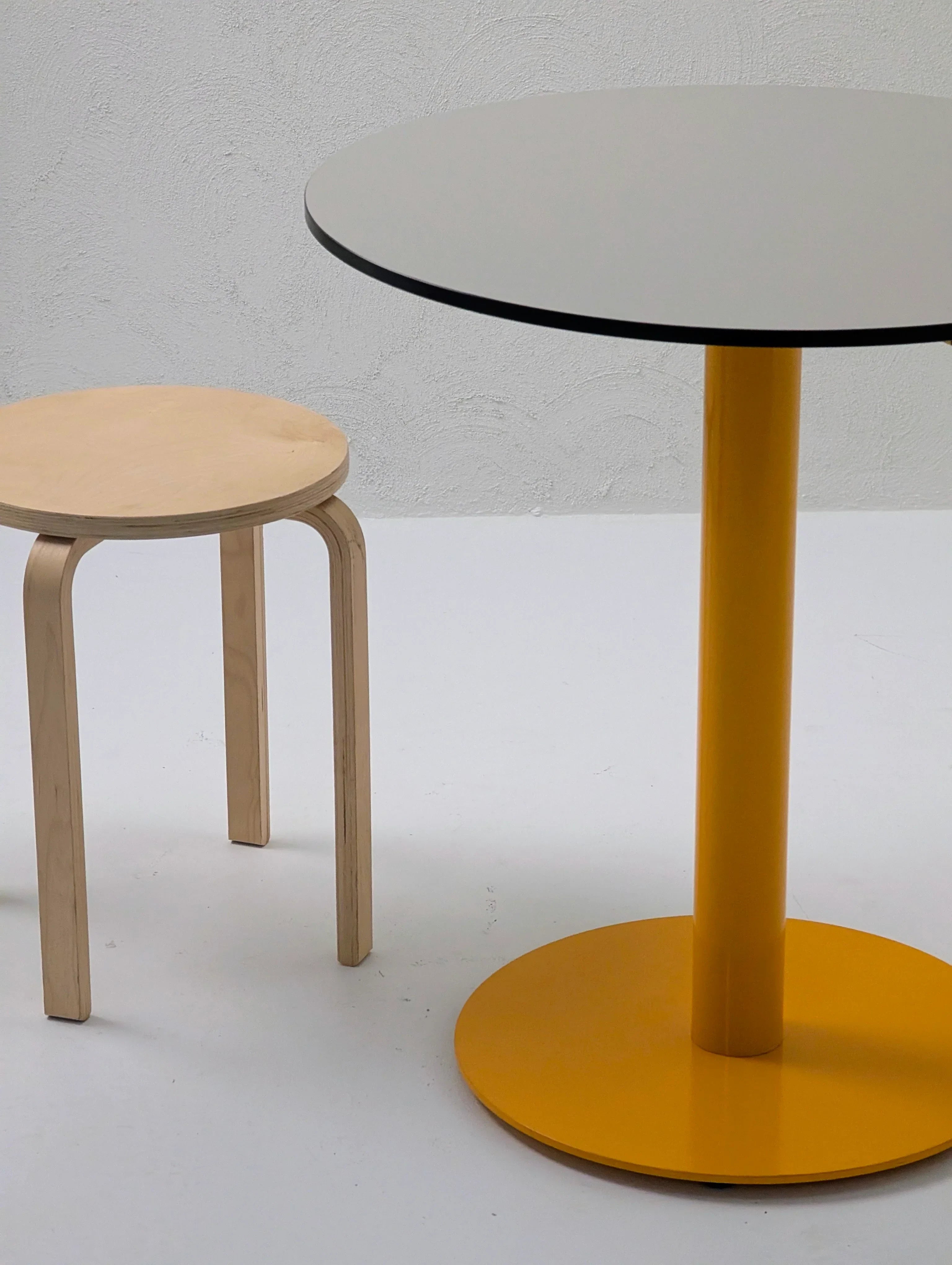 Minimalist round yellow table with light wood stool on white background