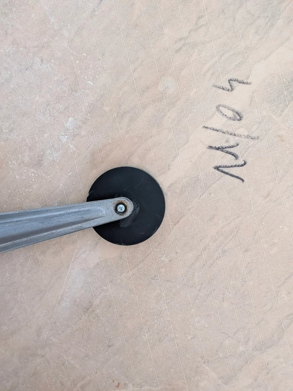 Tile cutter scoring ceramic tile with pencil markings and textured surface