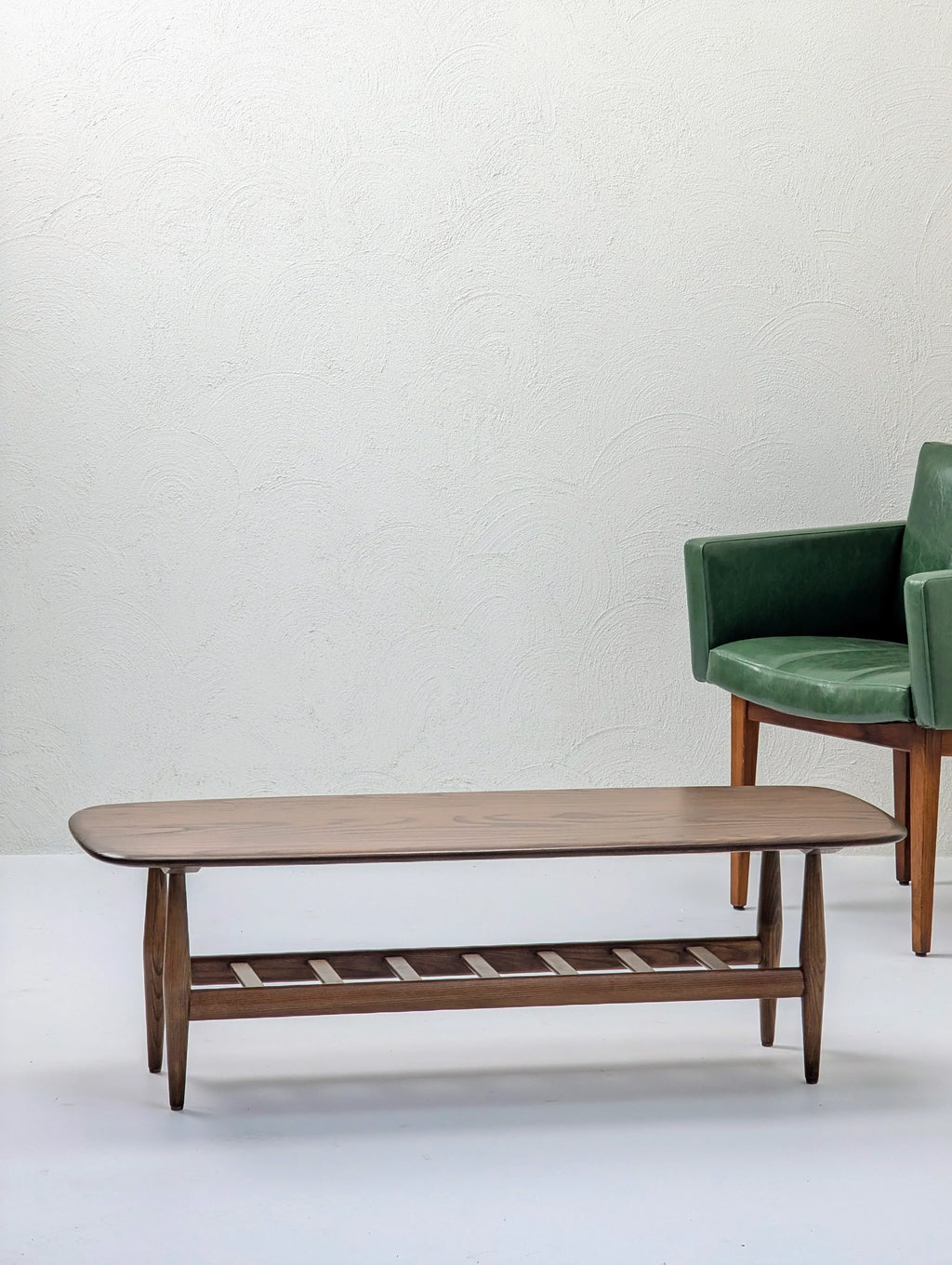 Mid-century modern wooden coffee table with green armchair on white background