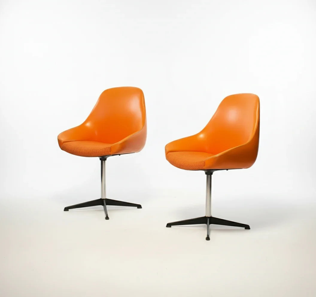 Two modern orange swivel chairs with cushioned seats on black metal bases against white background