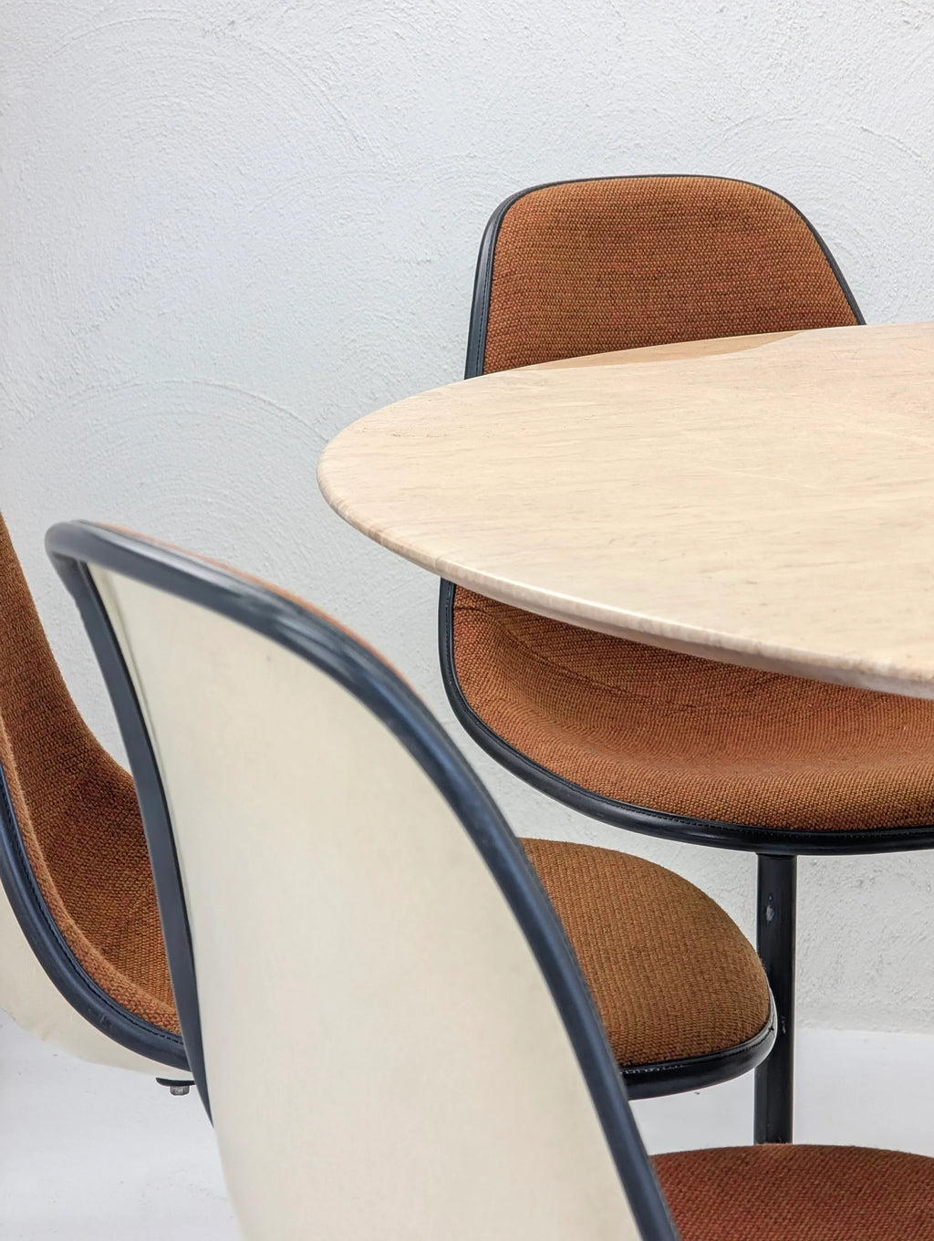 Mid-century modern dining chairs with orange upholstery and a round beige table