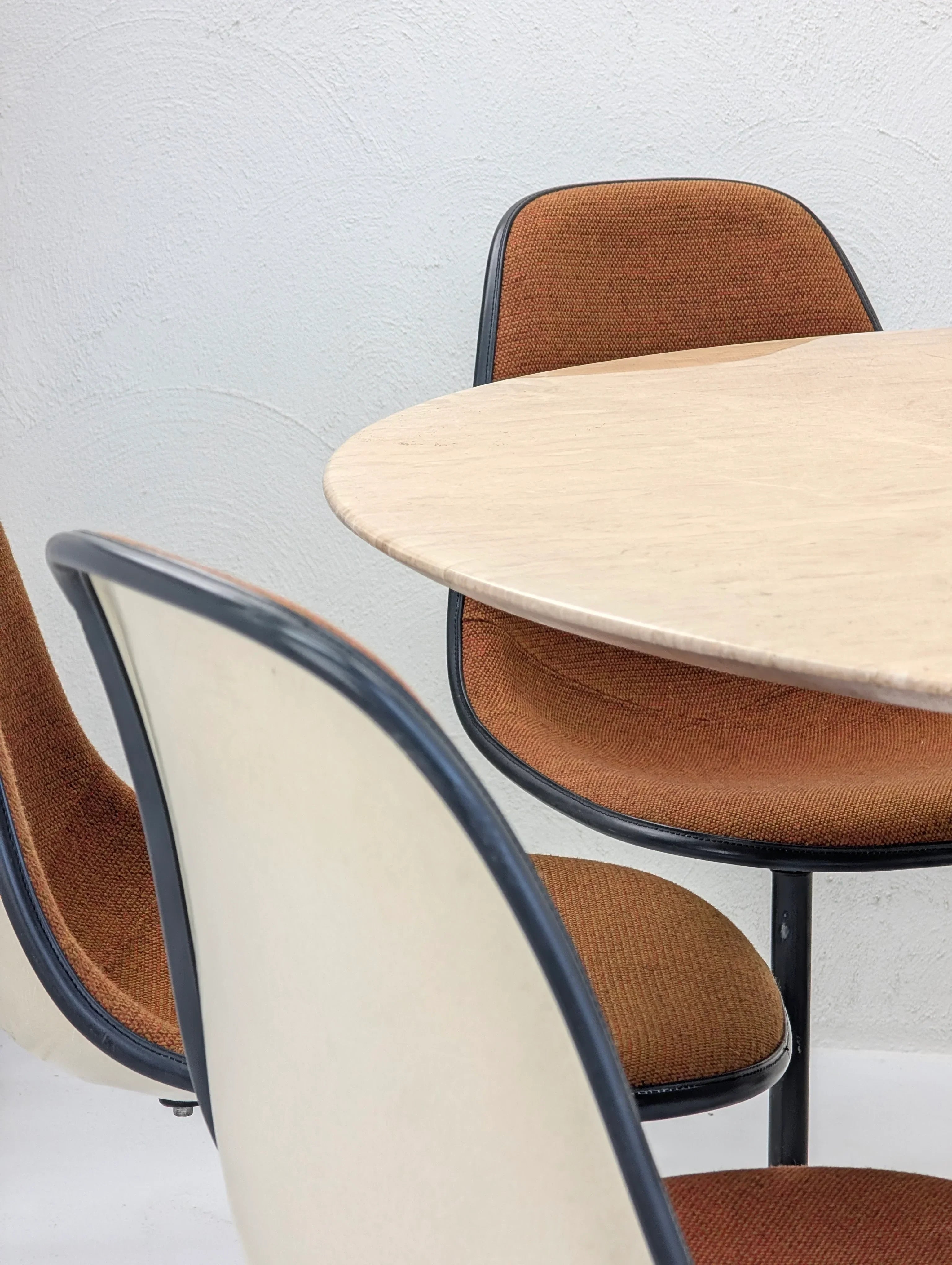 Mid-century modern dining chairs with orange upholstery and a round beige table