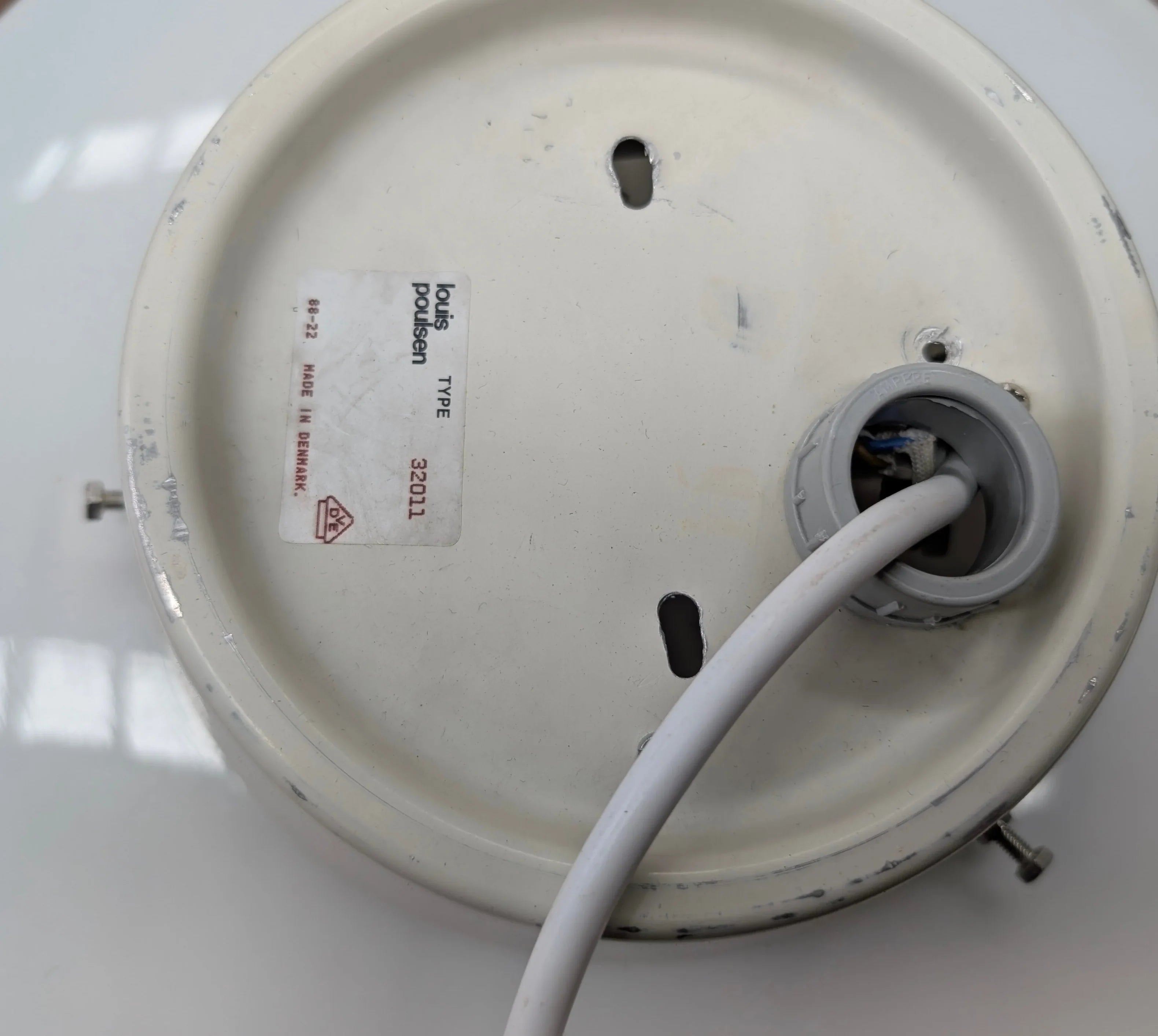 Bottom view of Louis Poulsen white round ceiling lamp base with wiring and mounting holes