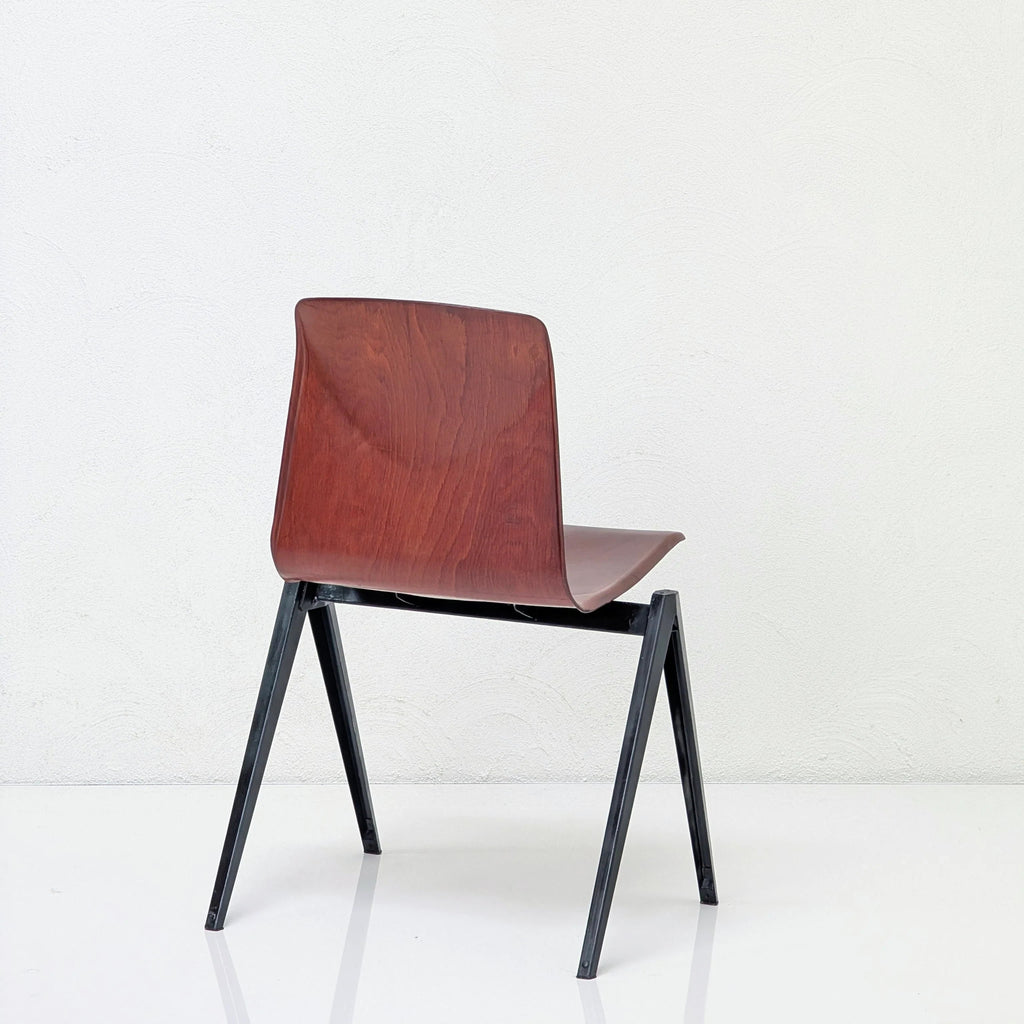 Modern chair with dark wood seat and black metal legs against white wall