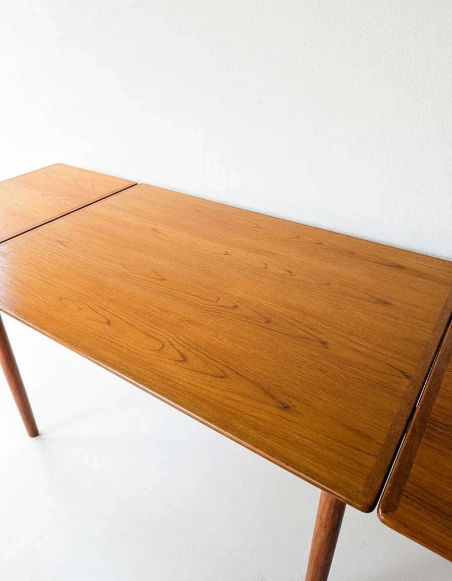 Minimalist wooden table with natural grain finish against a white wall and floor