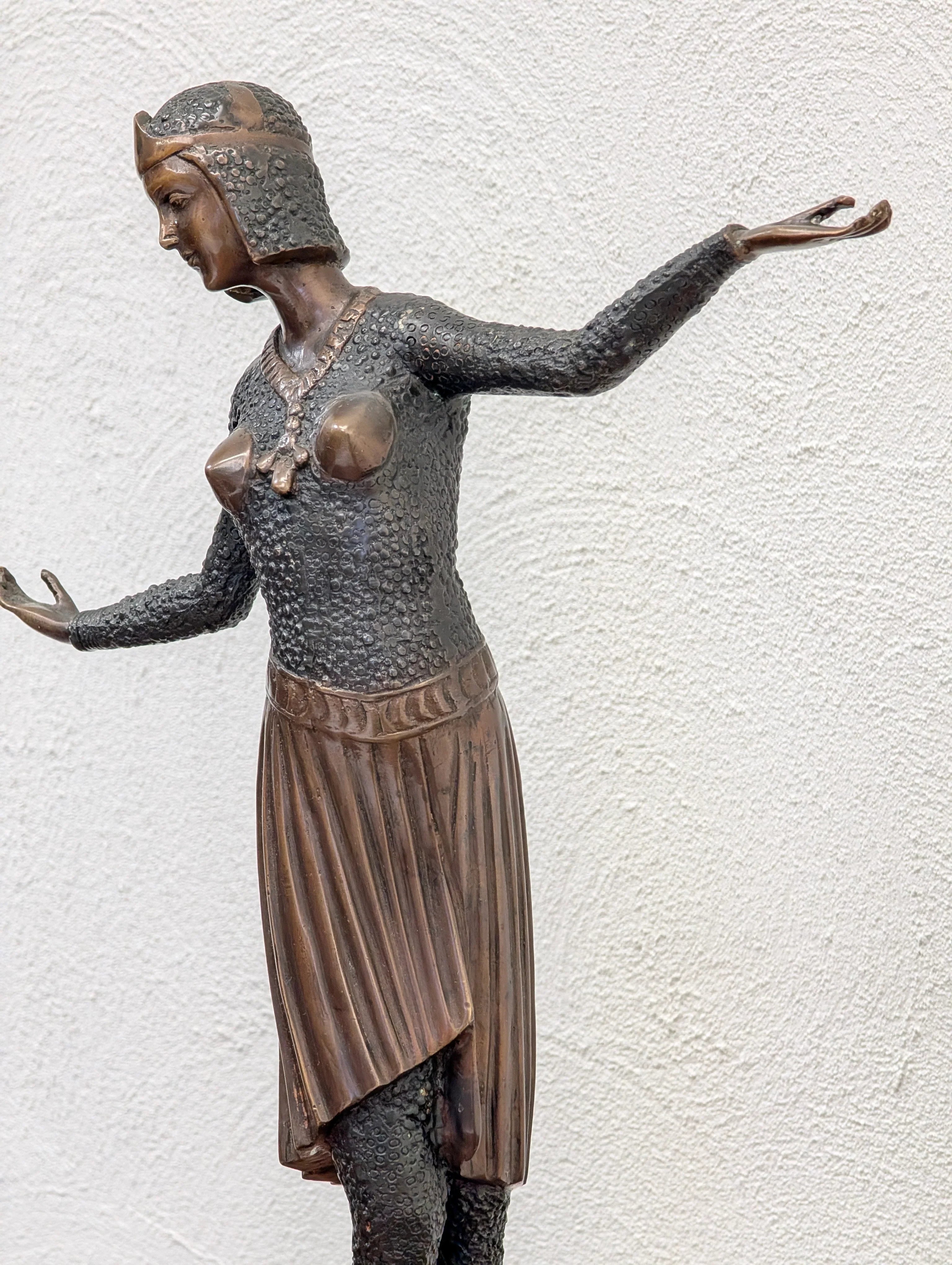 Bronze medieval female warrior statue with chainmail armor and pleated skirt against white wall