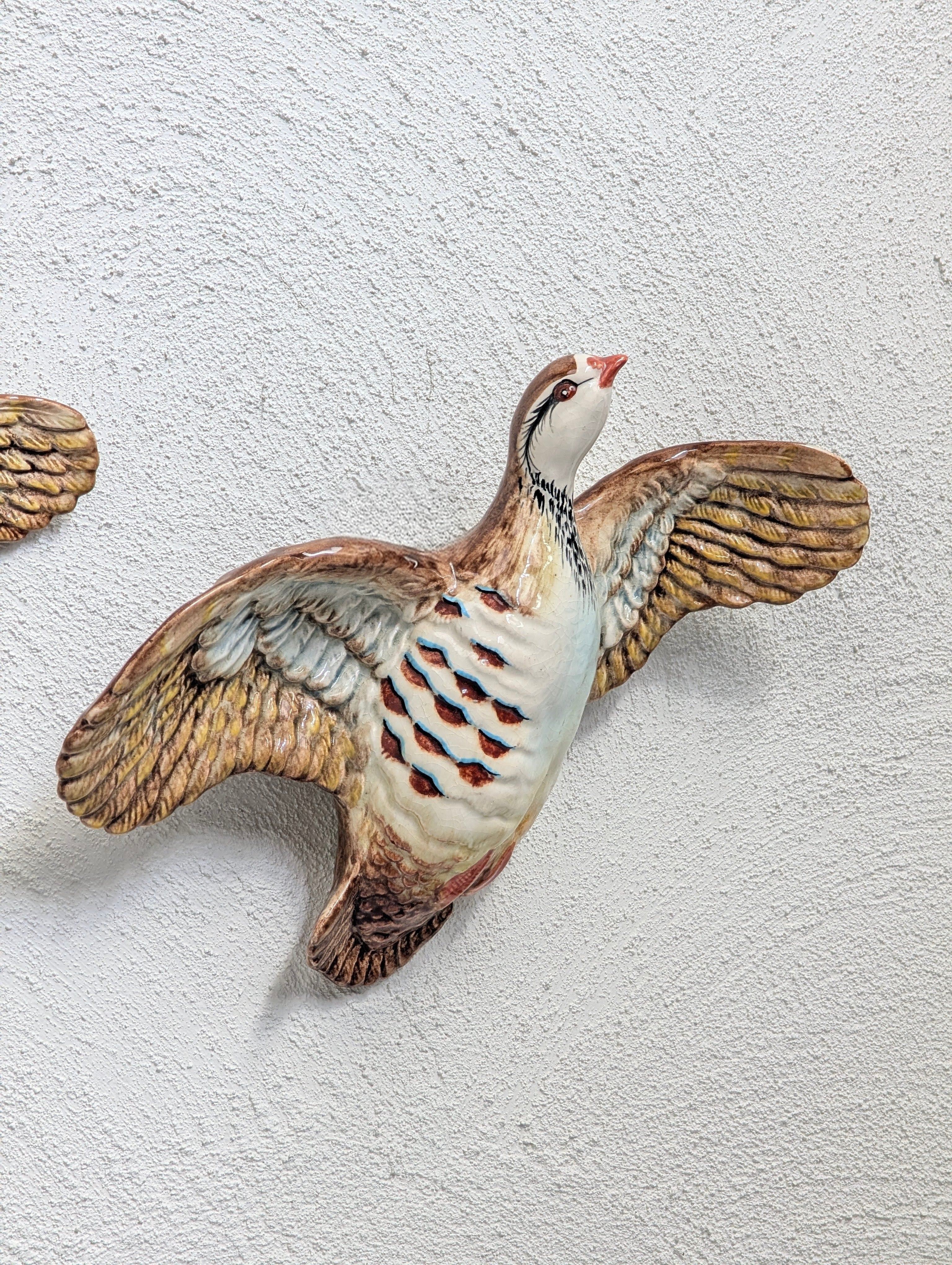 Ceramic quail wall decoration with wings spread mounted on textured white wall
