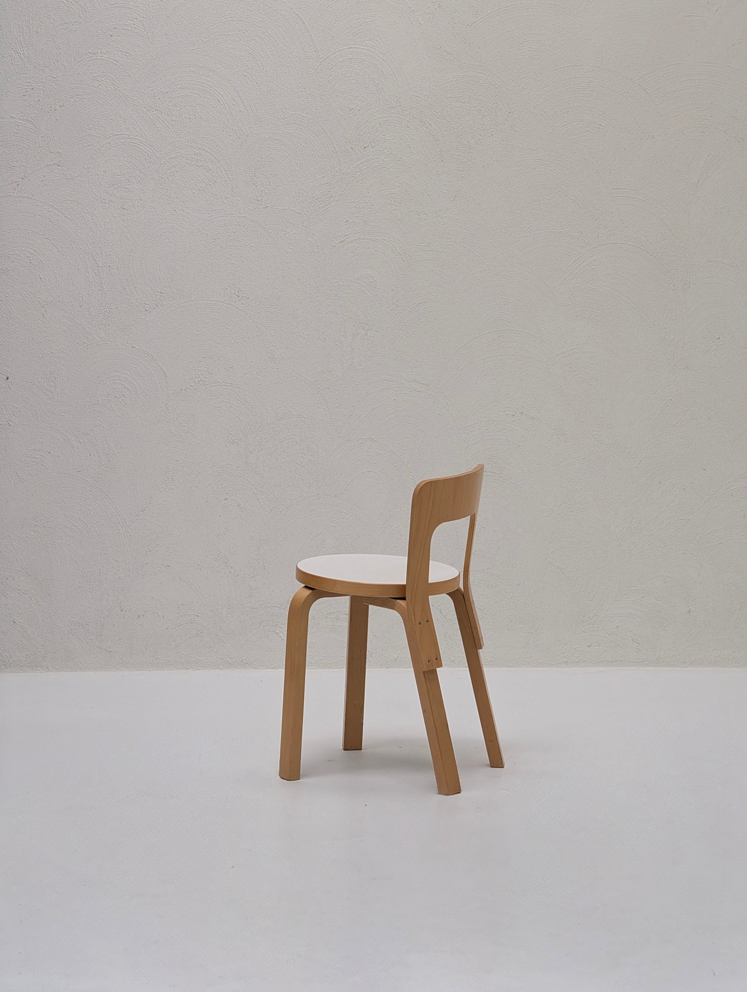 Minimalist wooden chair with white seat in front of textured white wall, modern design