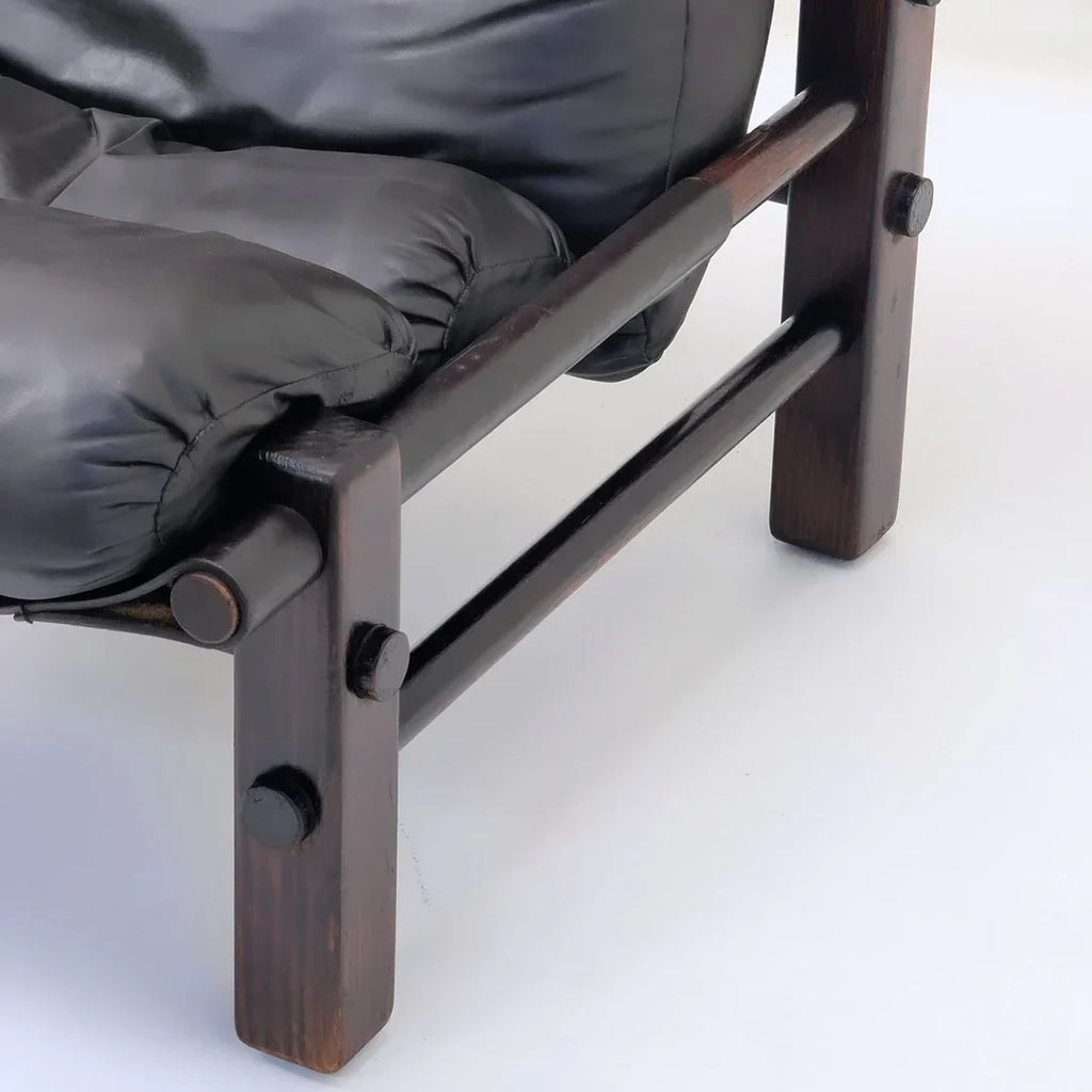 Close-up of a modern chair with dark wood frame and black leather cushion on white background