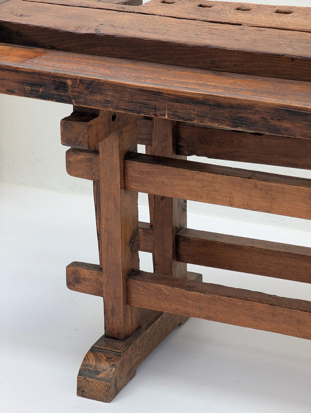 Close-up of rustic wooden workbench legs with visible grain, set on white floor