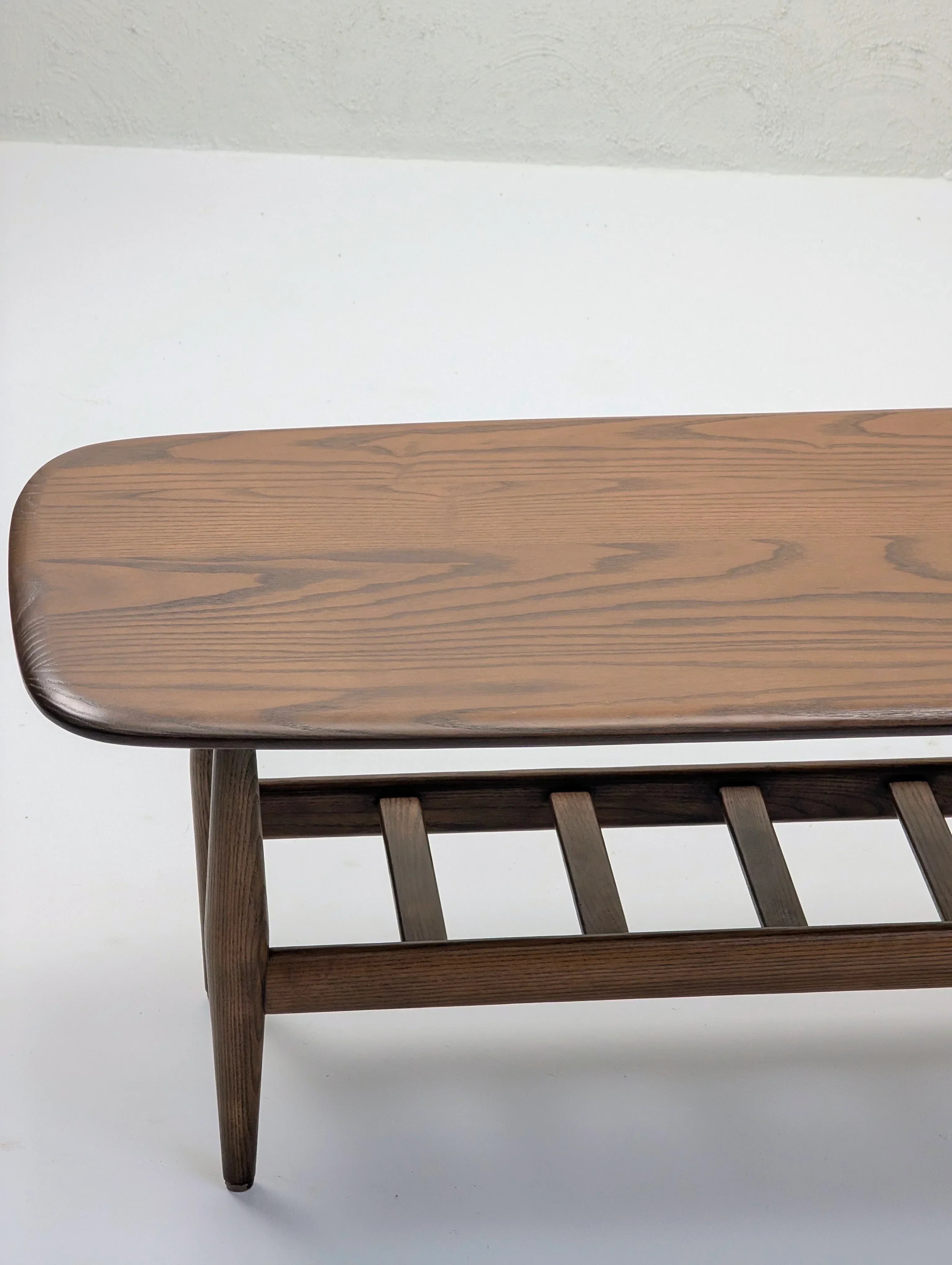 Mid-century modern wooden coffee table with slatted shelf on white background