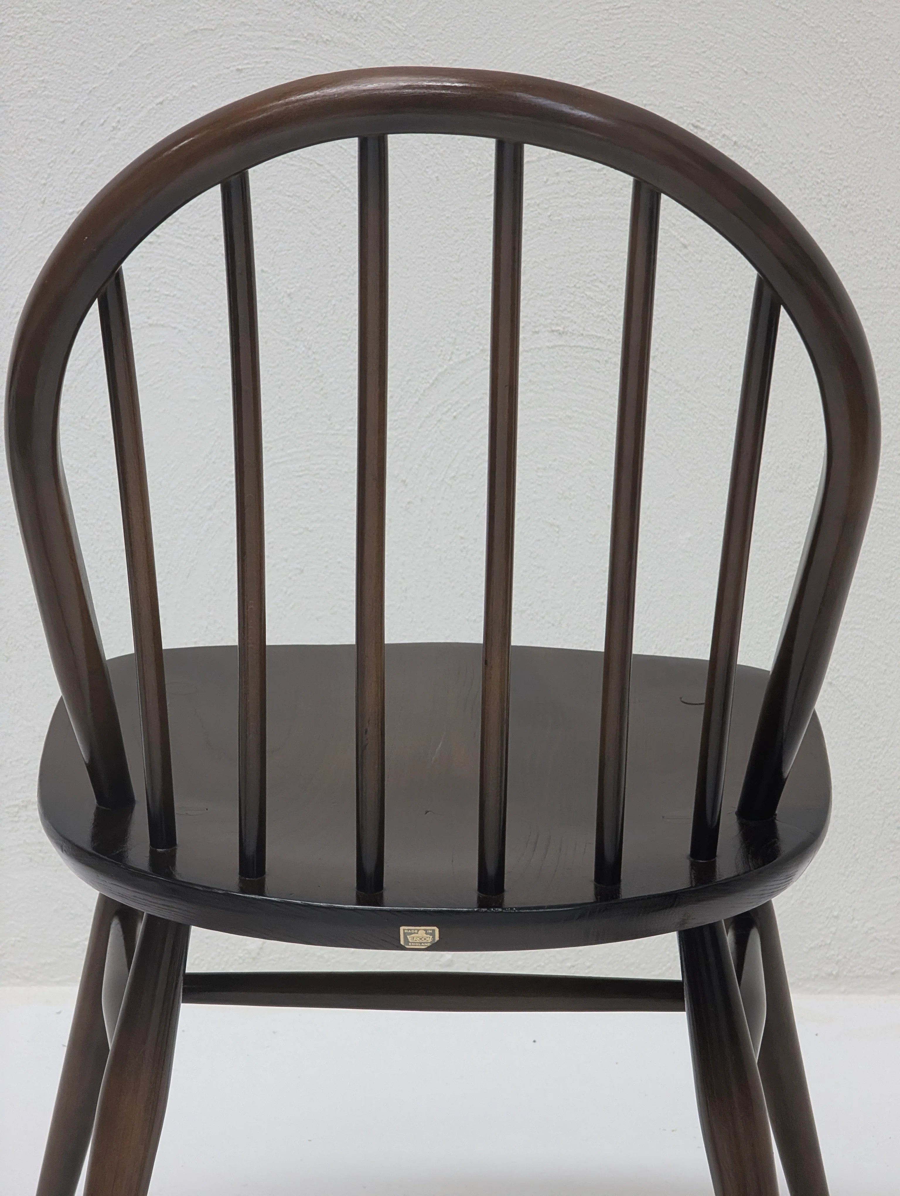 Dark wooden Windsor chair with rounded back and vertical slats against white wall