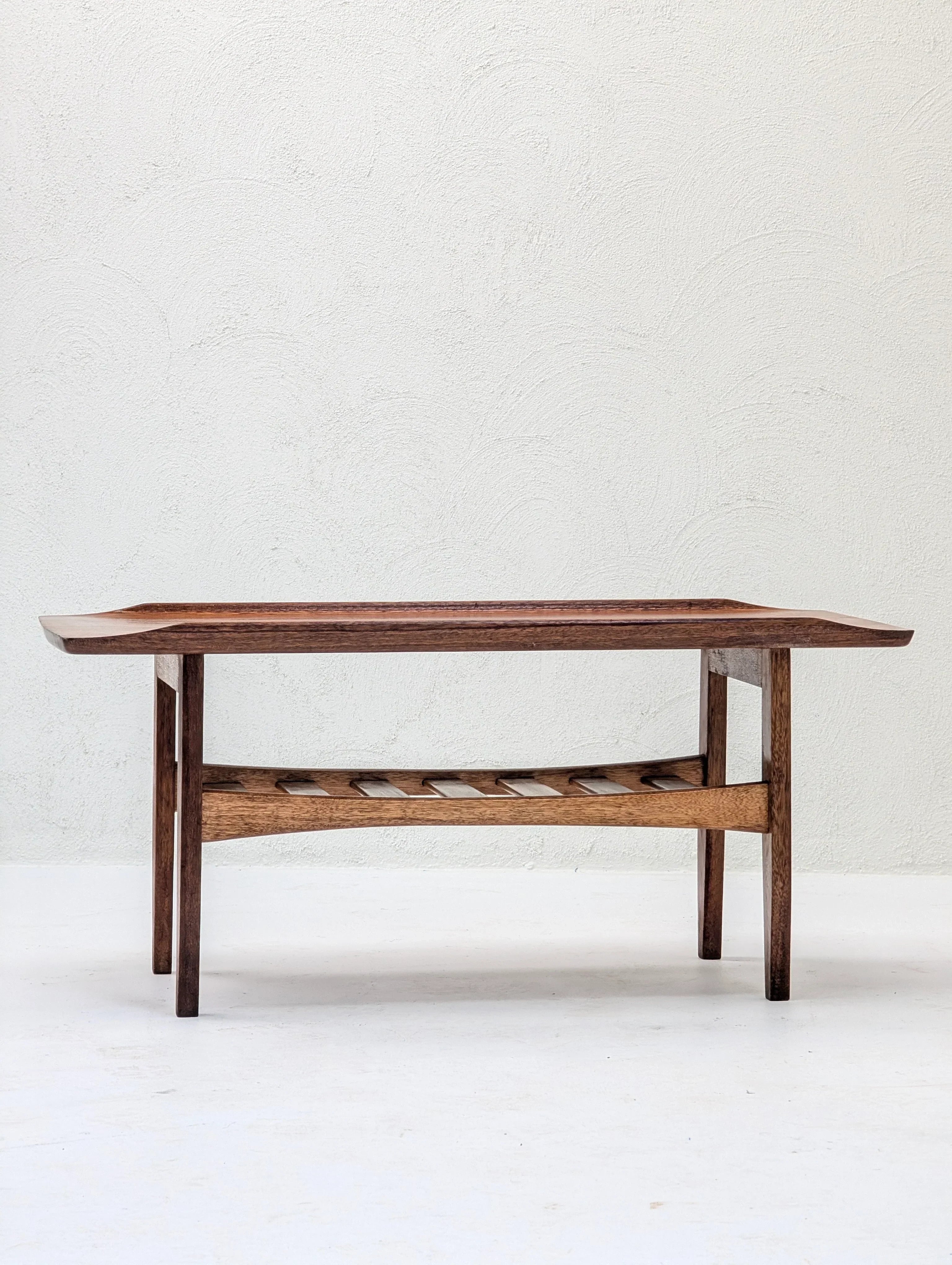 Mid-century modern wooden coffee table with slatted shelf on white background